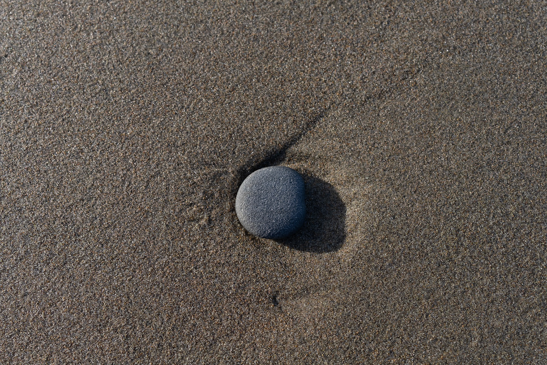 Perhaps because I missed seeing the April 8th 2024 eclipse due to cloud cover, even though I was in the zone of totality, in this sea-worn pebble, I see the moon blocking the sun, with the corona and solar flare visible.
