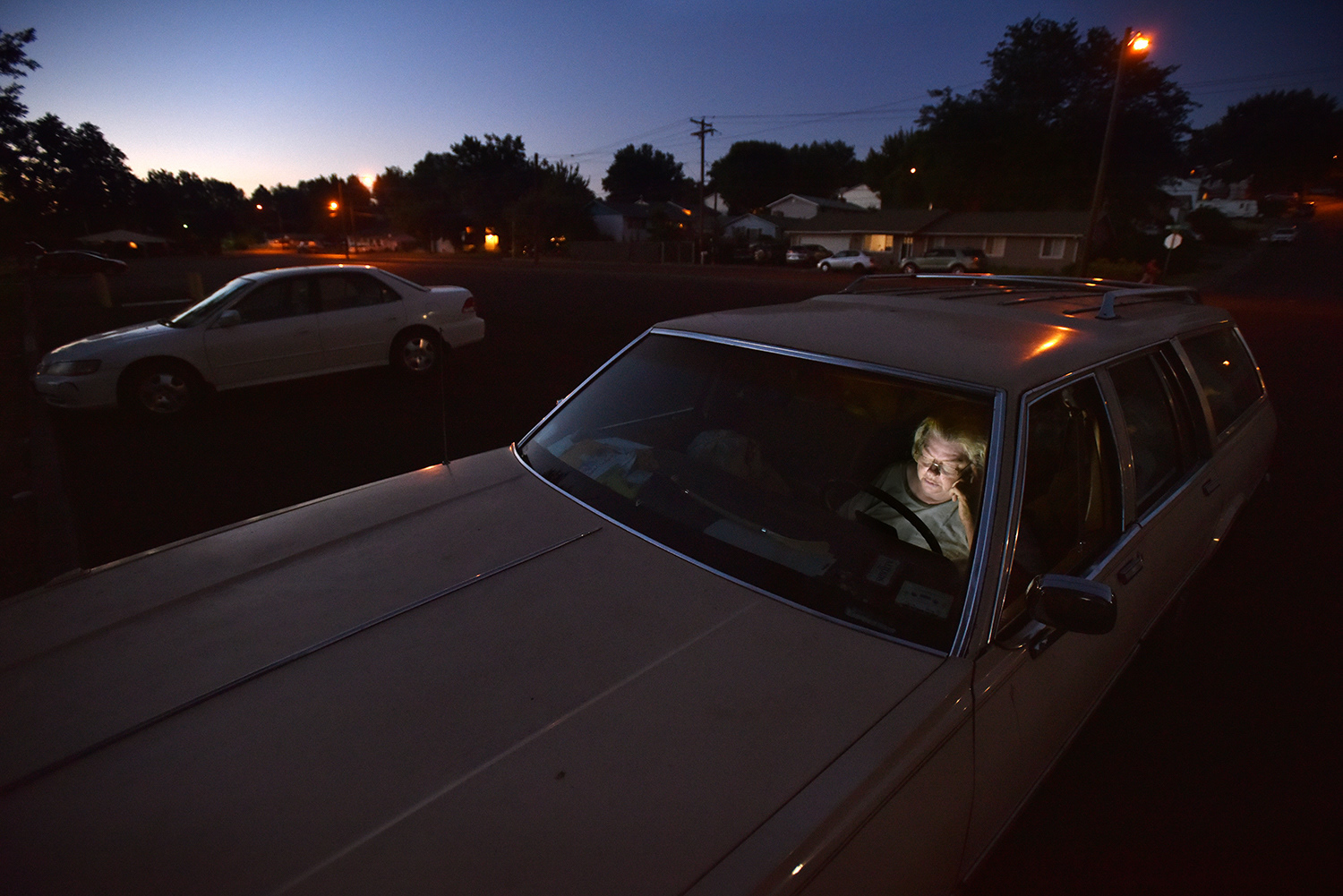 Linda Kuppenbender checks her messages on a tablet while sitting in her car at Community Parks on Wednesday, July 25, 2018, in Pendleton, Oregon. Kuppenbender, who is homeless, will stay in town until after dark before driving out of the city limits to find a place to park her car and bed down for the evening.