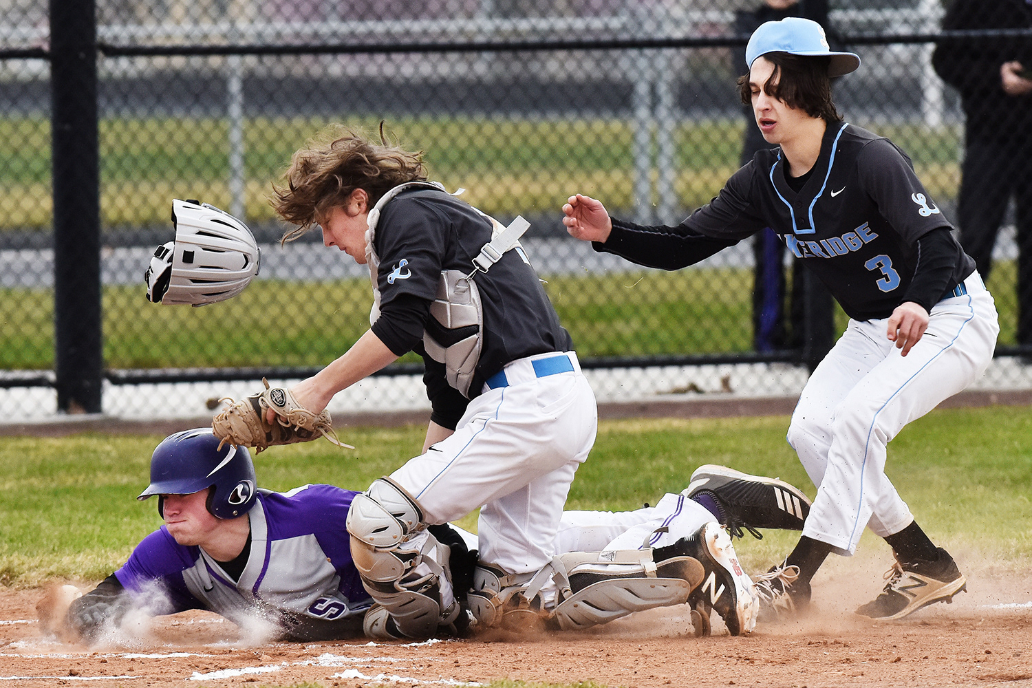 Hermiston’s Wyatt Noland slides safely into home after colliding with both Lakeridge pitcher Spencer Santana (3) and catcher Trent Allen in the Bulldogs’ 13-3 win against the Pacers on Friday, March 23, 2018,  in Hermiston, Oregon.