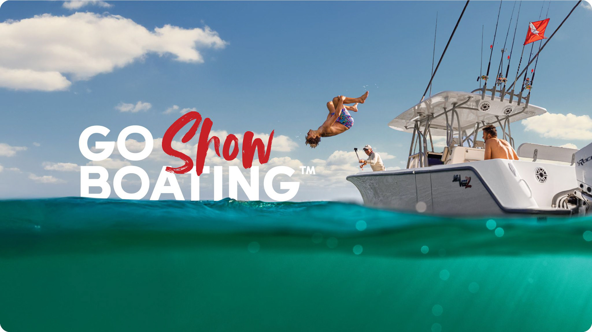 A man mid-backflip off the side of a fishing boat, captured half above and half below the water’s surface, with “Go Show Boating” text in the frame. Bright blue skies and clear turquoise water set the scene for this lifestyle marine campaign image.