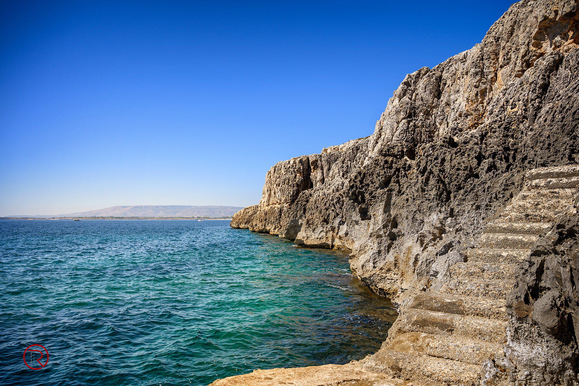 vista di costa marina con scale su roccia lavica in sicilia