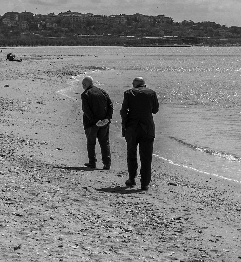 Küçükçekmece causeway (south side): 2 senior bald-headed men in suits strolling along the shore