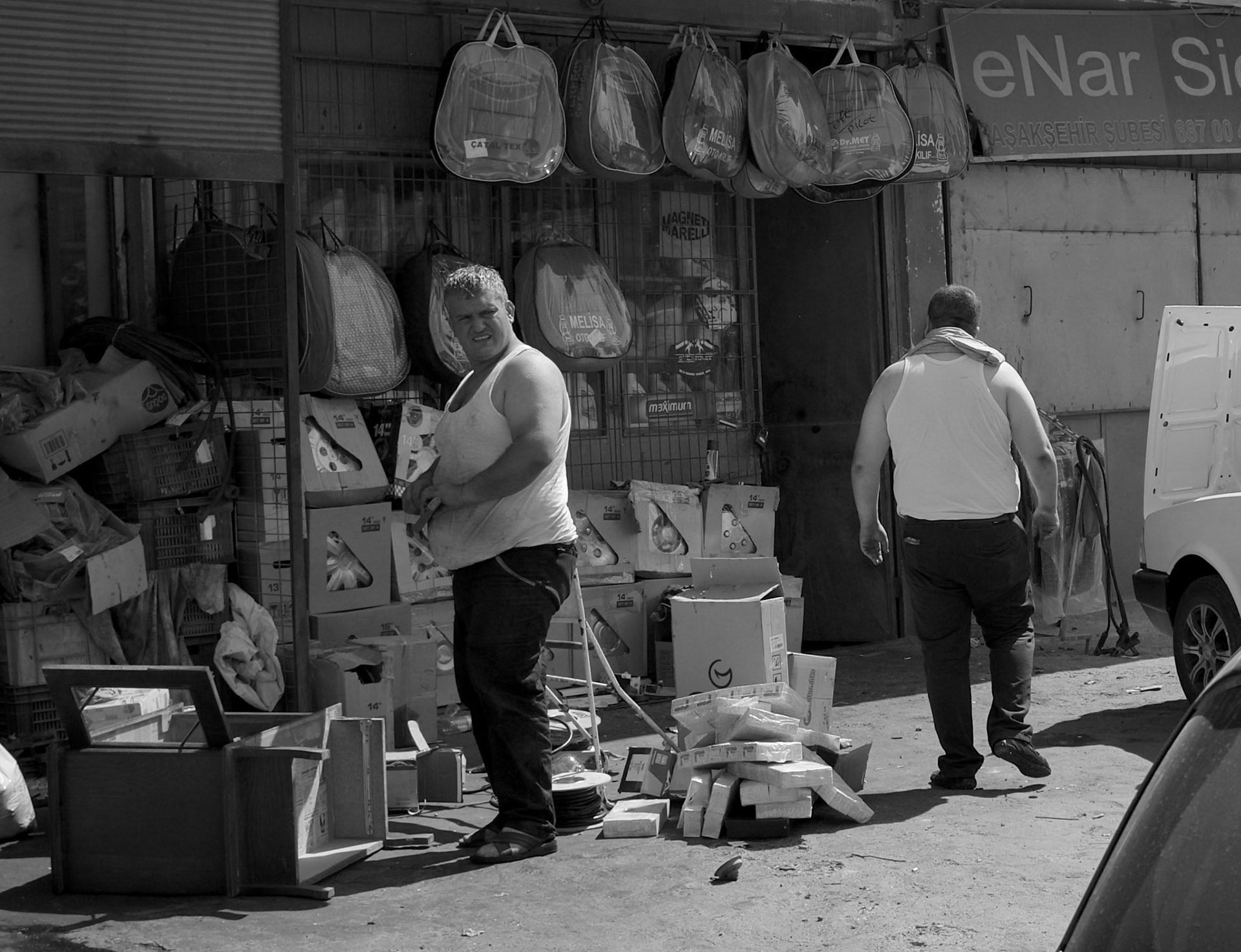 Altınşehir: cheerful big men working outside a roadside shop