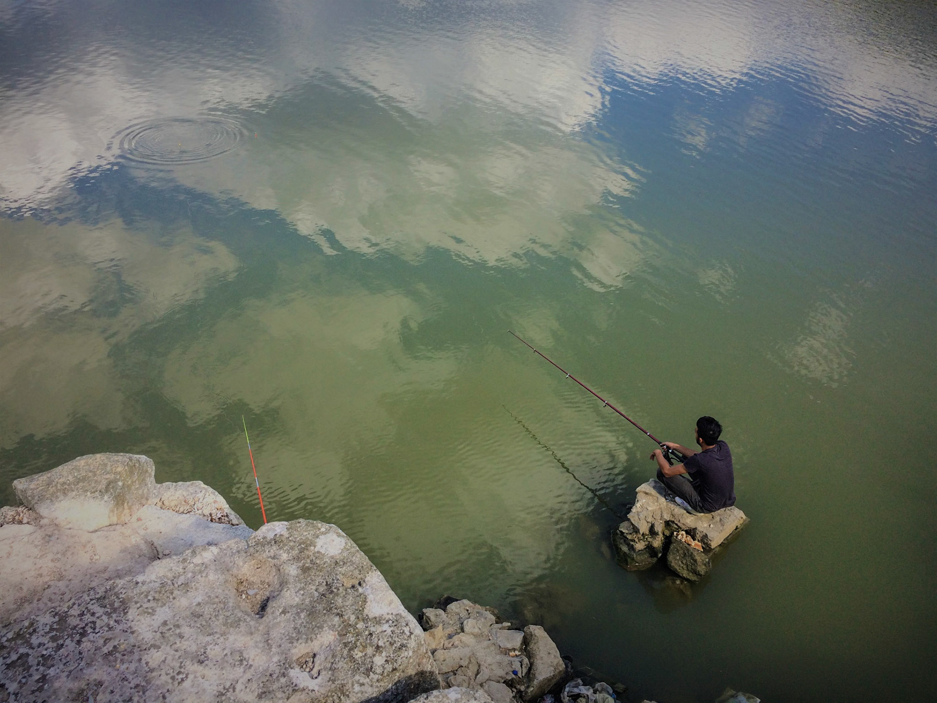 a fisherman on a rock in the Şamlar gorge reservoir just under the Ottoman dam