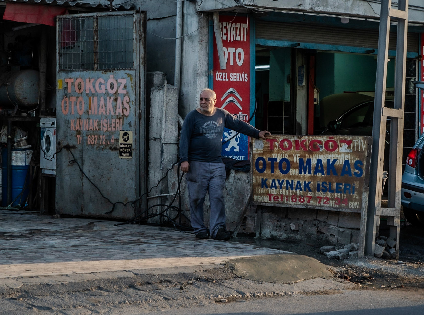 Altınşehir: a working man at a car repair workshop by the perpetually traffic-choked road through the township