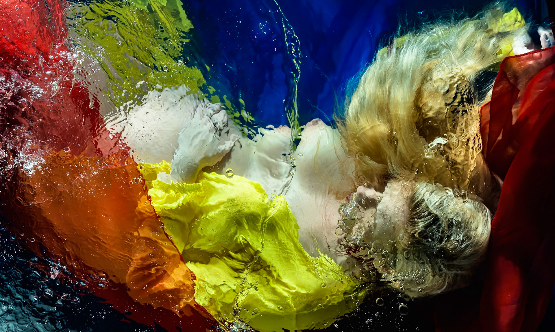 Erin was photographed in her eighth month of pregnancy. She is under water and lit by custom built underwater flashes. The photo is captured from above the water and has minimal post processing applied. The suspension in liquid of the model and fabrics give a soft and ethereal quality to the subject. The distortions and ripples of surface disturbance lend a painterly and expressionistic quality to the image.