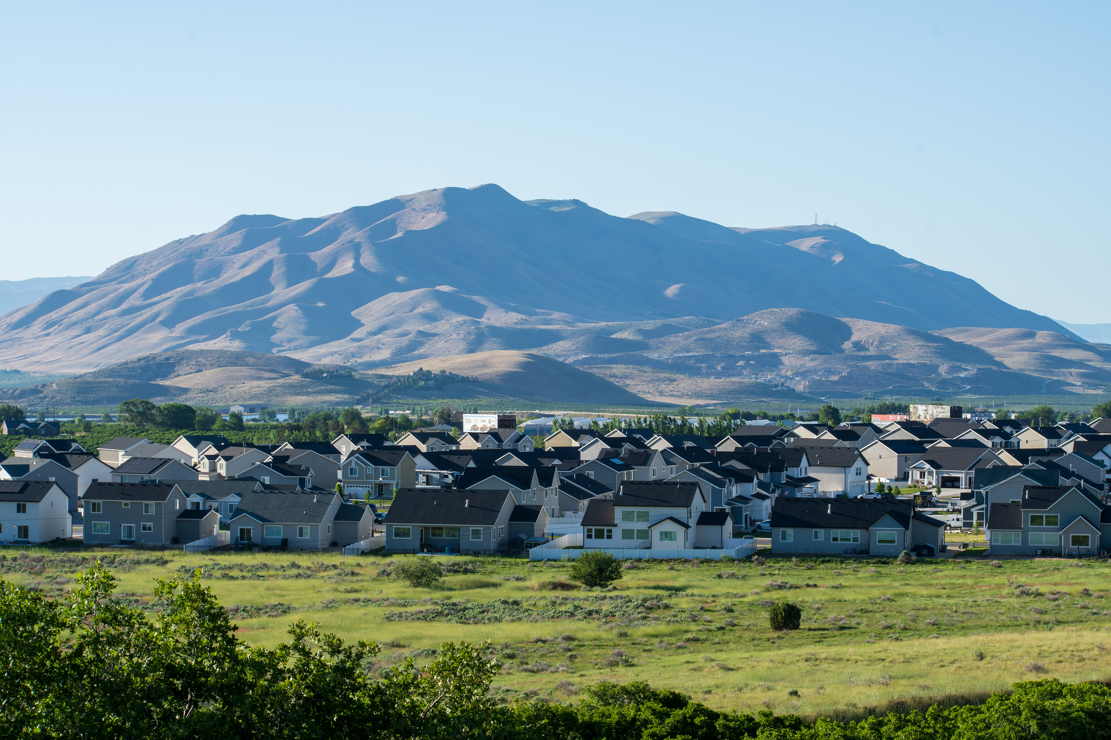 Santaquin, Utah – June 2, 2025: Wide view of a residential neighborhood with a mountainous backdrop and open valley under a clear sky.