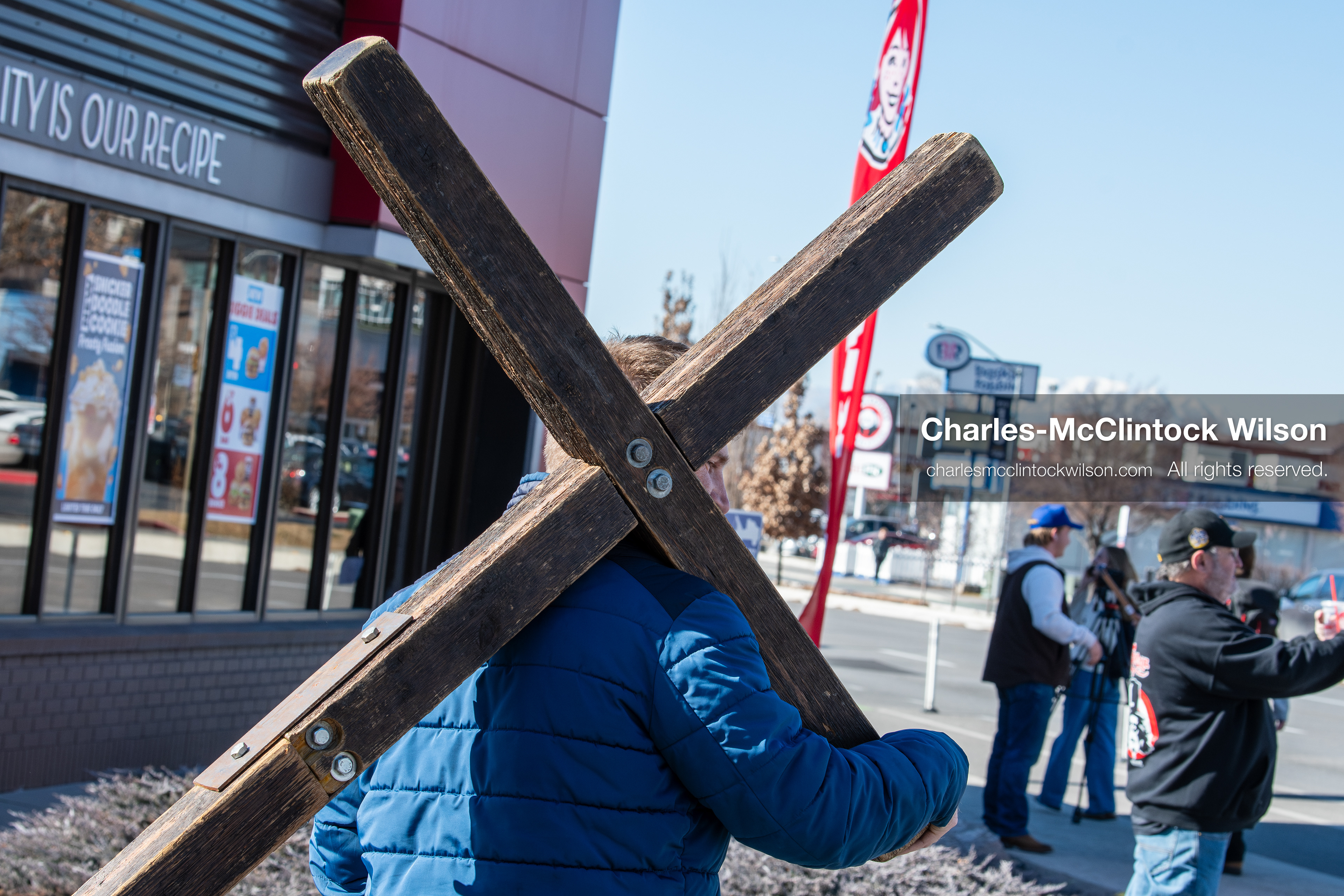 February 5, 2026, Provo, Utah, USA: A man carries a wooden cross while walking near Brigham Young University in Provo during a protest opposing the presence of US Customs and Border Protection recruiters at a career fair held on the BYU campus. (Credit Image: © Charles McClintock Wilson/ZUMA Press Wire)
