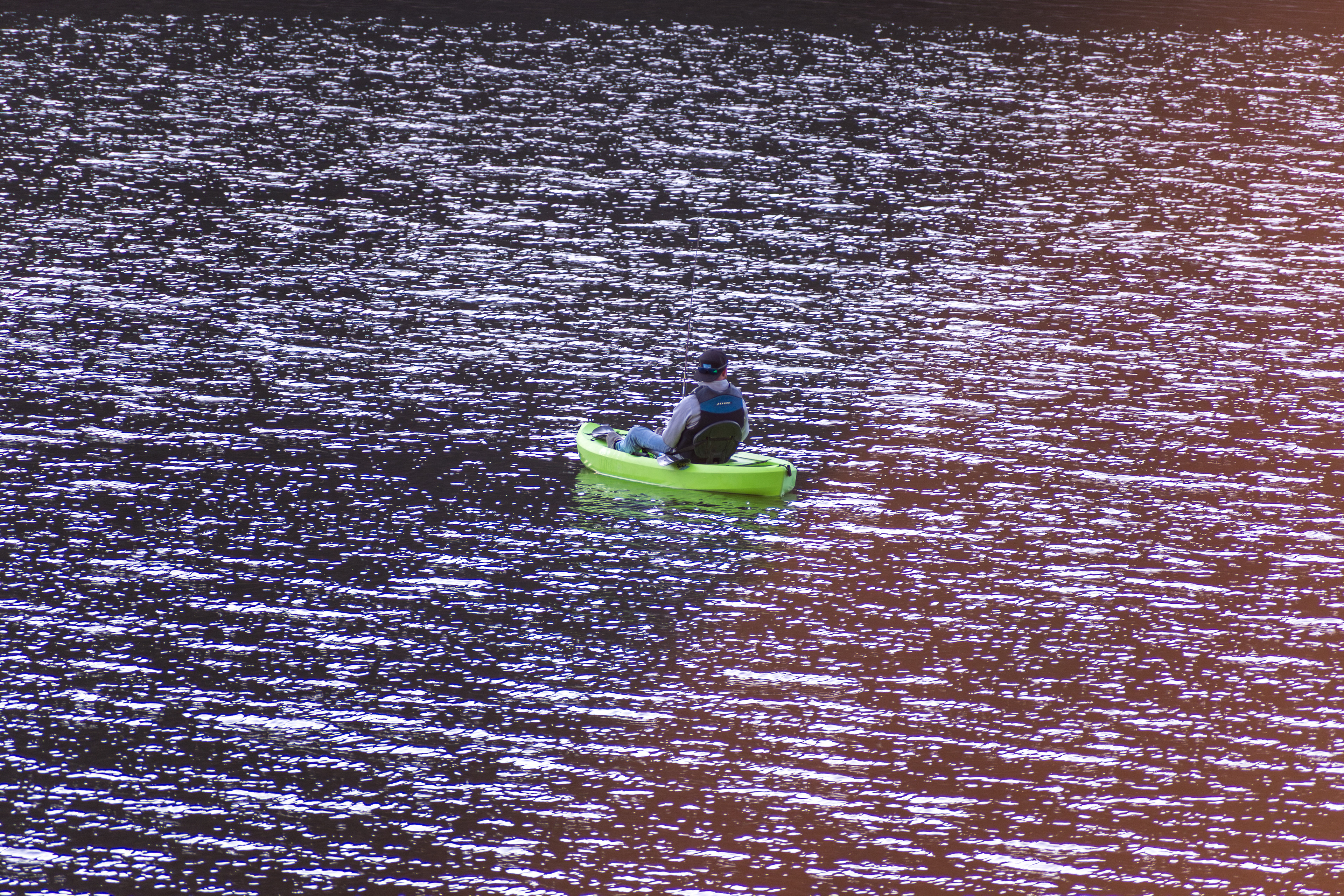 Summit County, Utah – July 20, 2025: A man paddles a bright green kayak while fishing at Smith and Morehouse Reservoir.