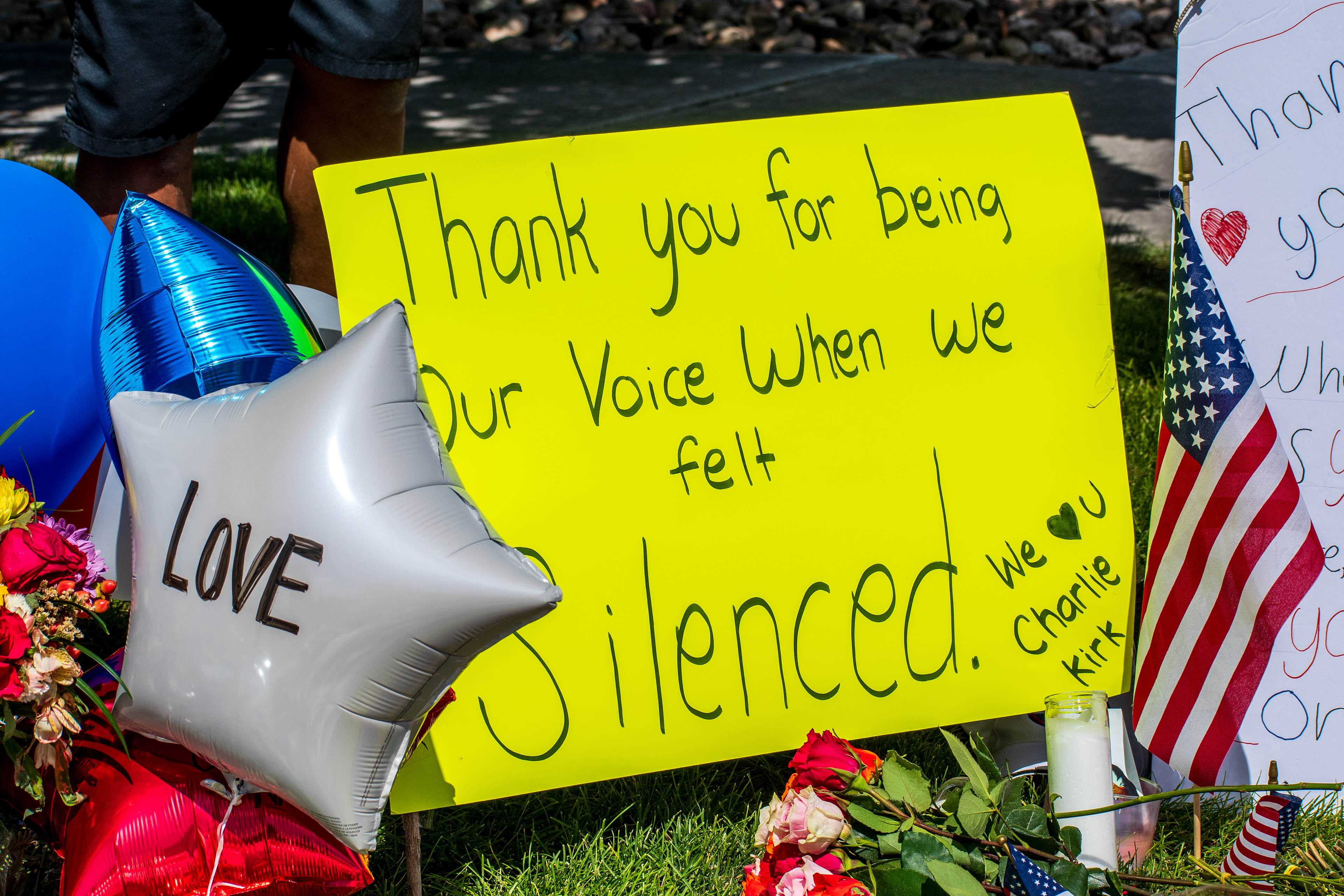 OREM, UTAH – SEPTEMBER 12, 2025: A silver balloon marked “LOVE” rises above flowers, handwritten posters, and an American flag at a memorial site for Charlie Kirk near Utah Valley University. A yellow sign reads, “Thank you for being Our Voice When we felt Silenced,” reflecting a public gesture of appreciation and remembrance. © Charles‑McClintock Wilson / ZUMA Press