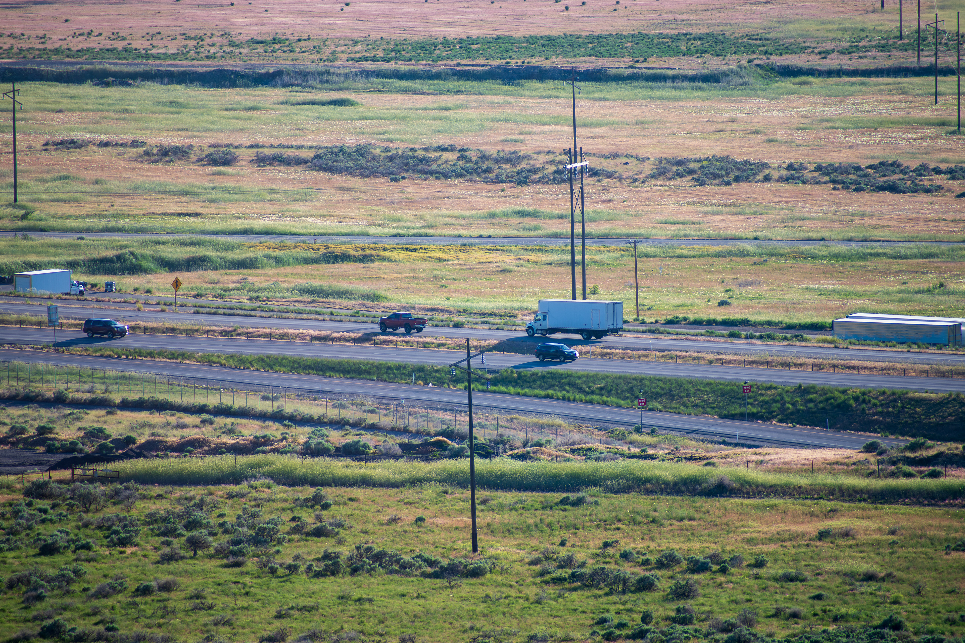 Santaquin, Utah – June 2, 2025: A distant view captures vehicles traveling along Interstate 15 as it winds through the valley near Santaquin, Utah, accompanied by power lines paralleling the roadway.