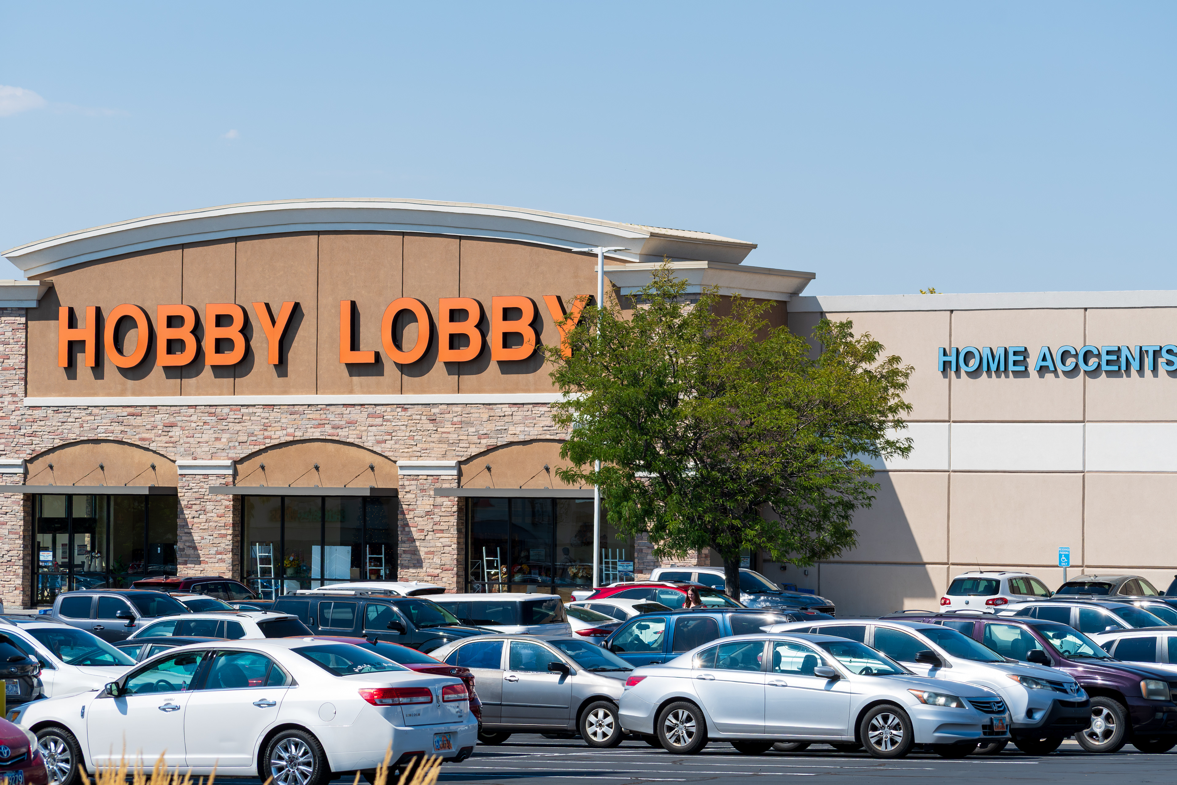 Orem, Utah, USA — September 1, 2025: Hobby Lobby’s orange-lettered signage crowns the entrance of its retail location, with a packed parking lot and “Home Accents” branding visible on the facade.
