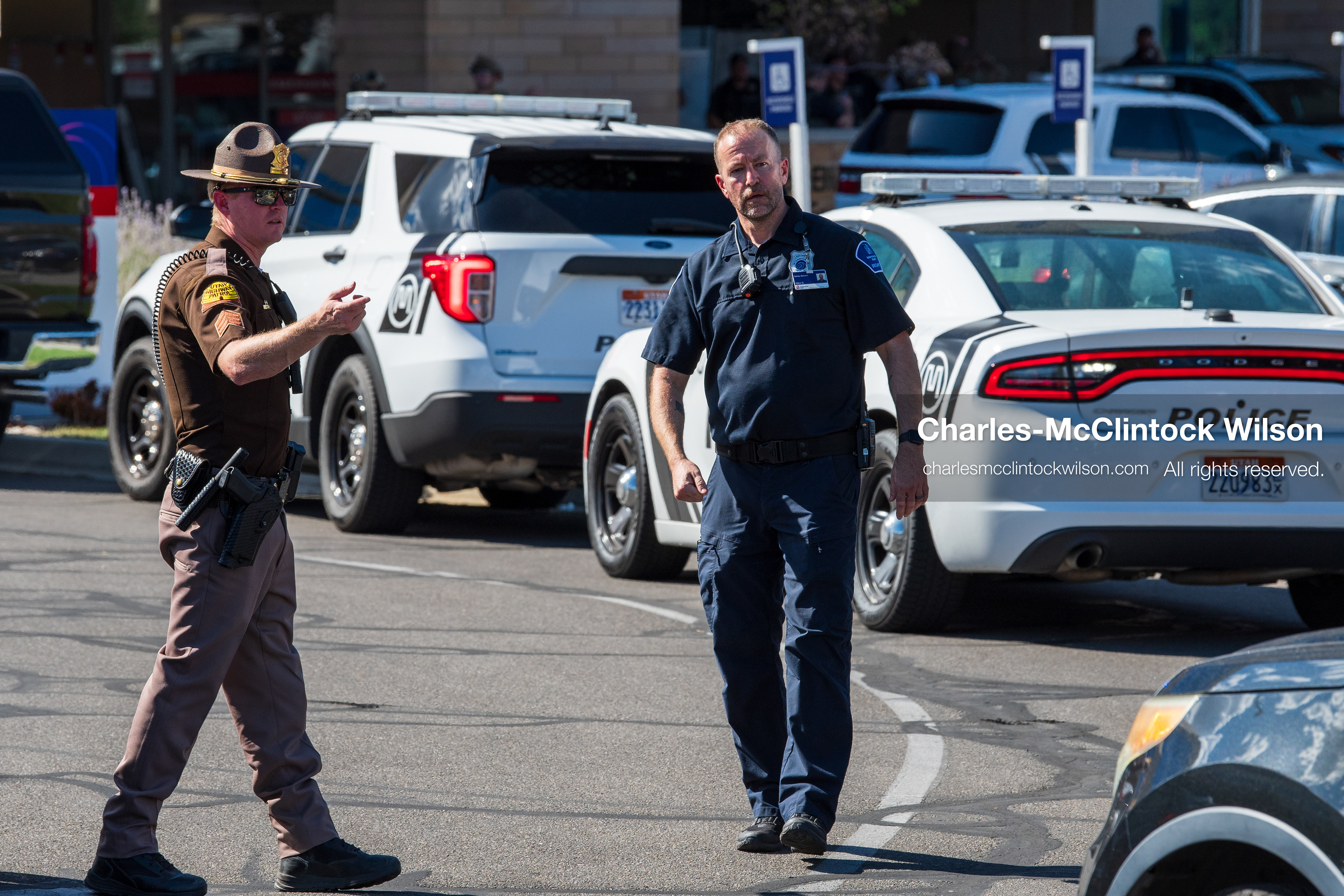 A Utah Highway Patrol trooper and a local police officer patrol past parked emergency vehicles outside Intermountain Medical Center in Murray, Utah, on Monday, August 17, 2026. Multiple regional law enforcement agencies converged to heavily secure the hospital perimeter as a safety precaution after shooting victims arrived from a fatal shootout that erupted outside a funeral service in nearby Kearns earlier that day. (Photo by Charles-McClintock Wilson/Sipa USA)