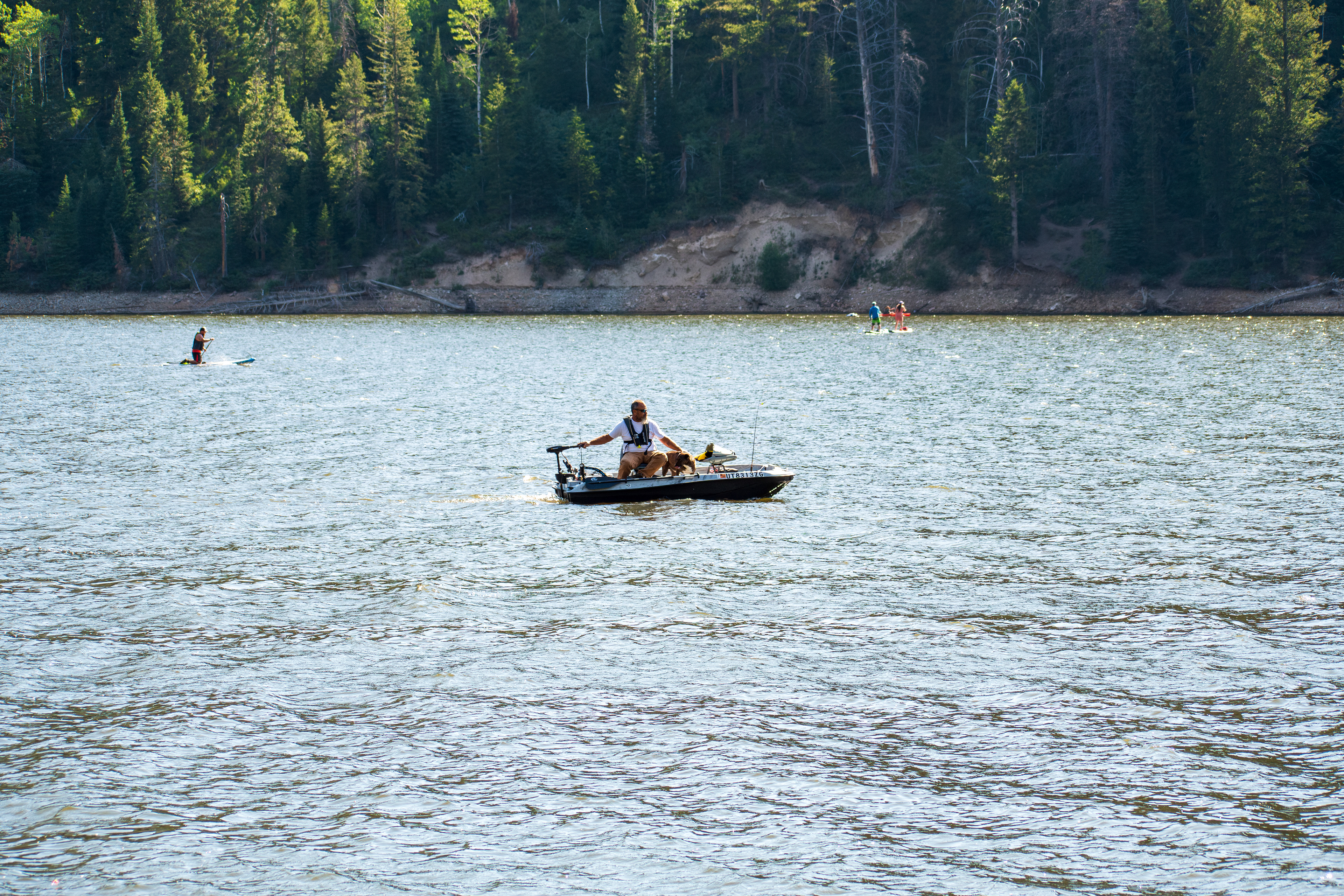 Summit County, Utah – July 20, 2025: A man and his dog ride together on a small boat at Smith and Morehouse Reservoir.