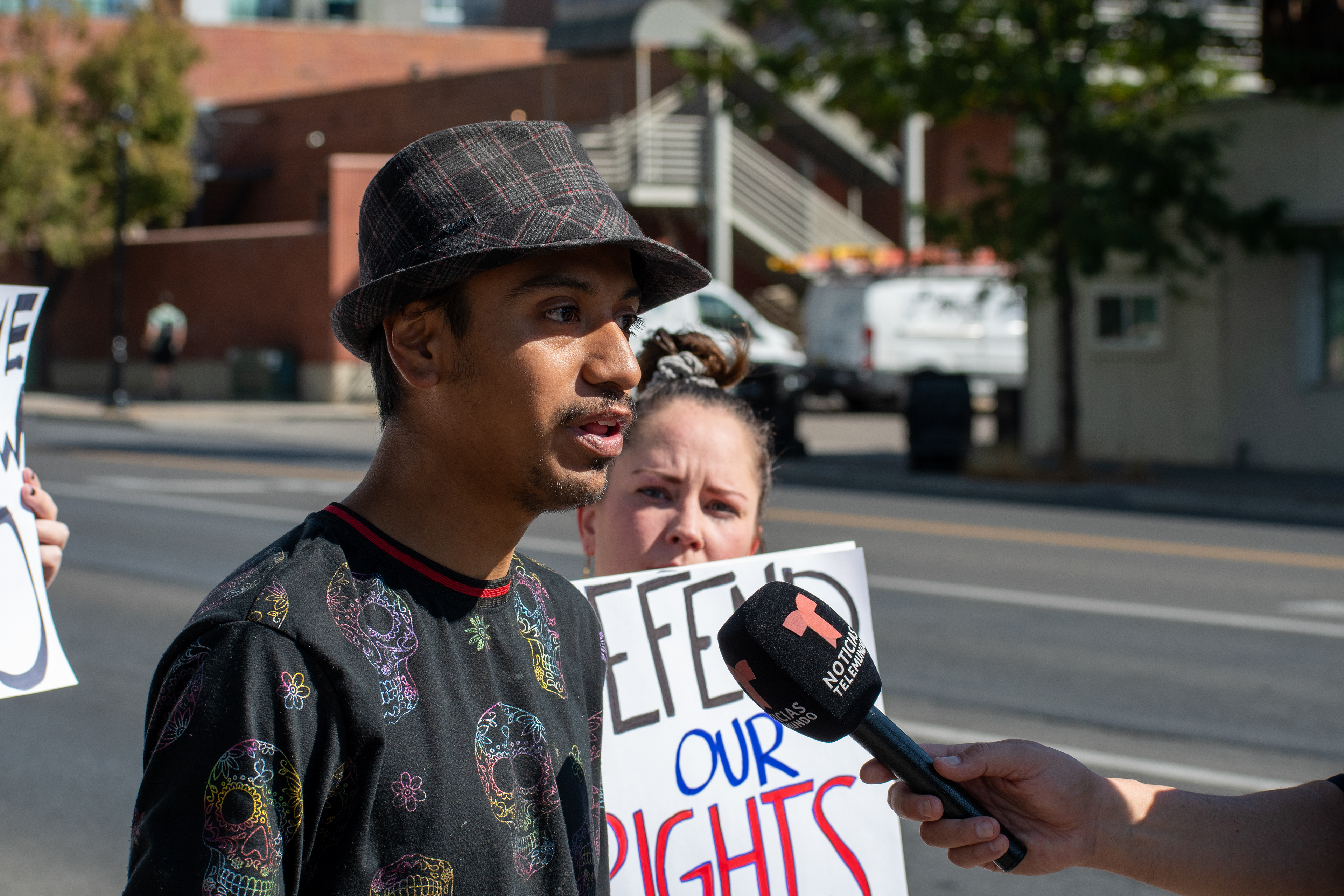 September 15, 2025 – Provo, Utah, United States: A demonstrator speaks to a Telemundo reporter during a protest outside the Utah Valley Convention Center against the Department of Homeland Security career expo. Behind him, another protestor holds a sign reading “DEFEND OUR RIGHTS,” as civic voices challenge federal recruitment and enforcement practices. Photograph by Charles‑McClintock Wilson / ZUMA Press Wire