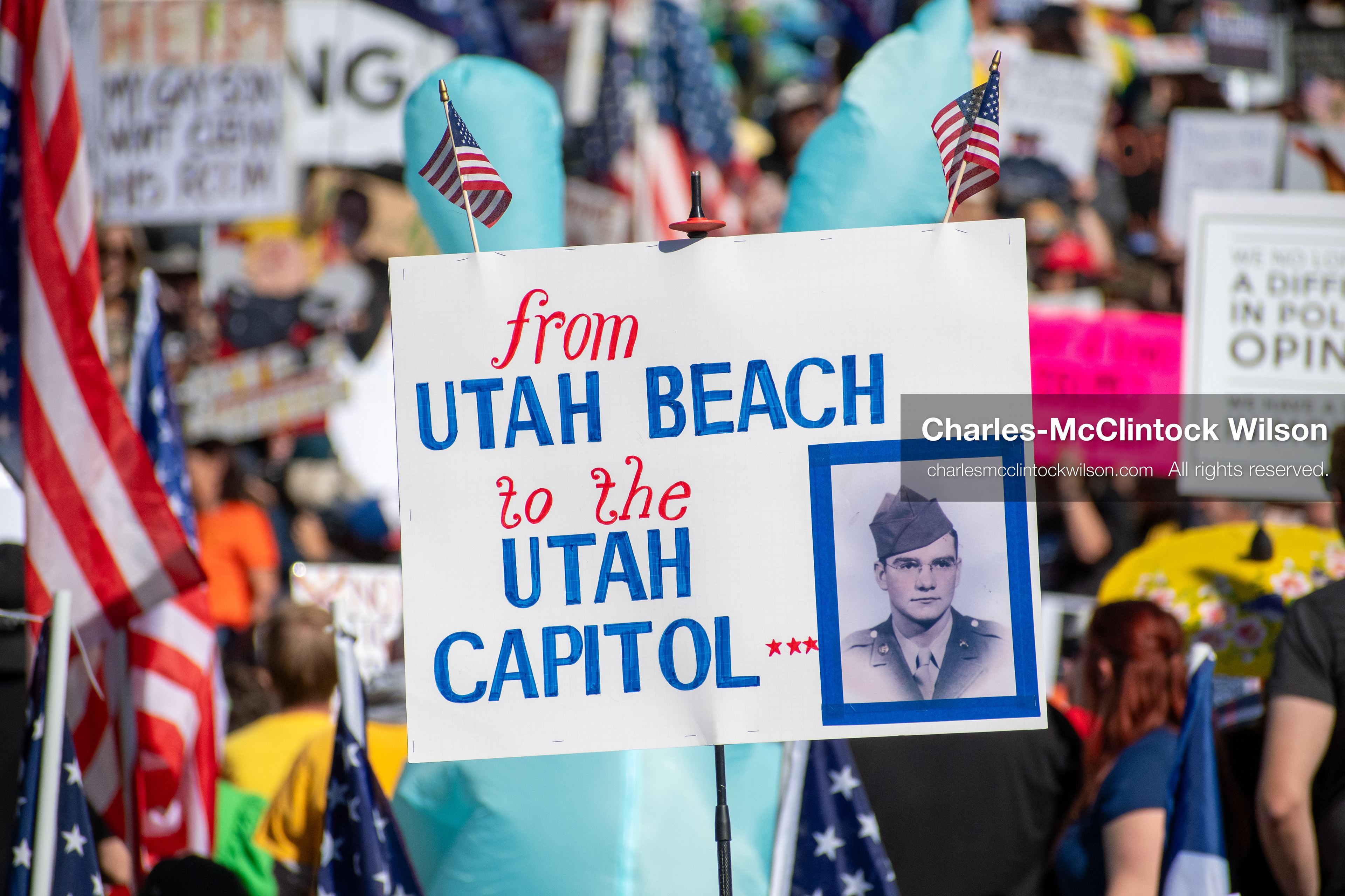 October 18, 2025, Salt Lake City, Utah, USA: A demonstrator raises a placard during a "No Kings" protest held at the Utah State Capitol. Other participants and signs are visible in the background during the public gathering.