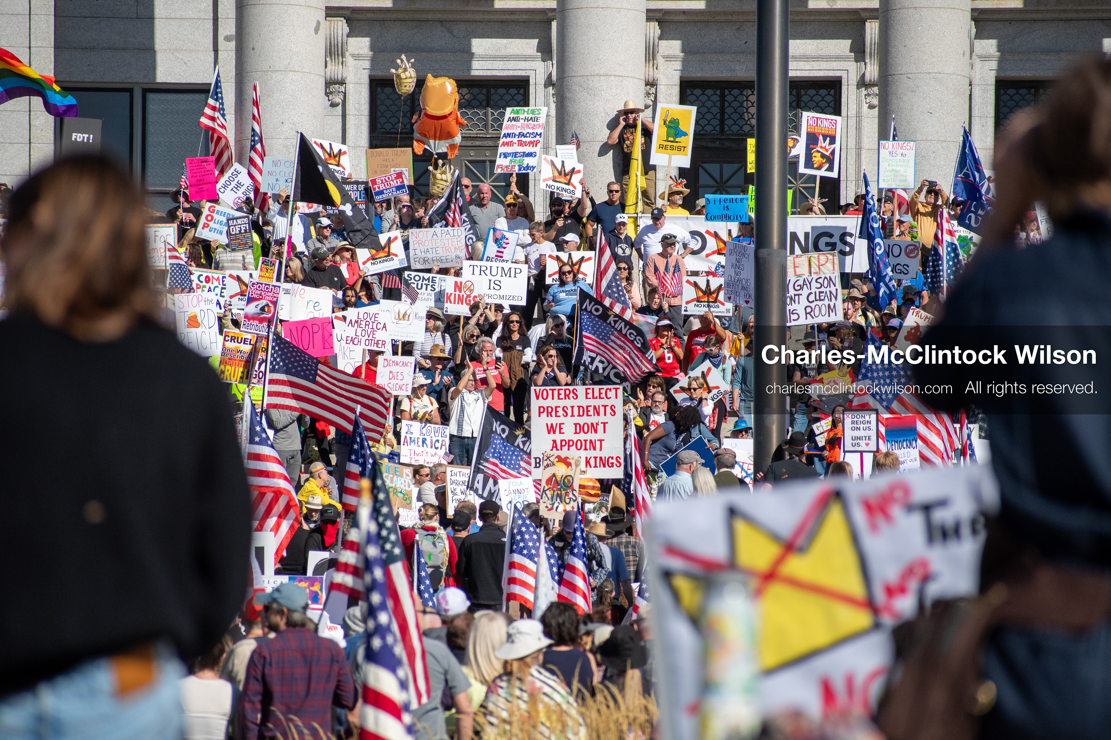 October 18, 2025, Salt Lake City, Utah, USA: Demonstrators gather on the steps of the Utah State Capitol during a "No Kings" protest held as part of a nationwide mobilization. Participants hold signs and flags while documenting the event. The protest was one of several organized across the United States.