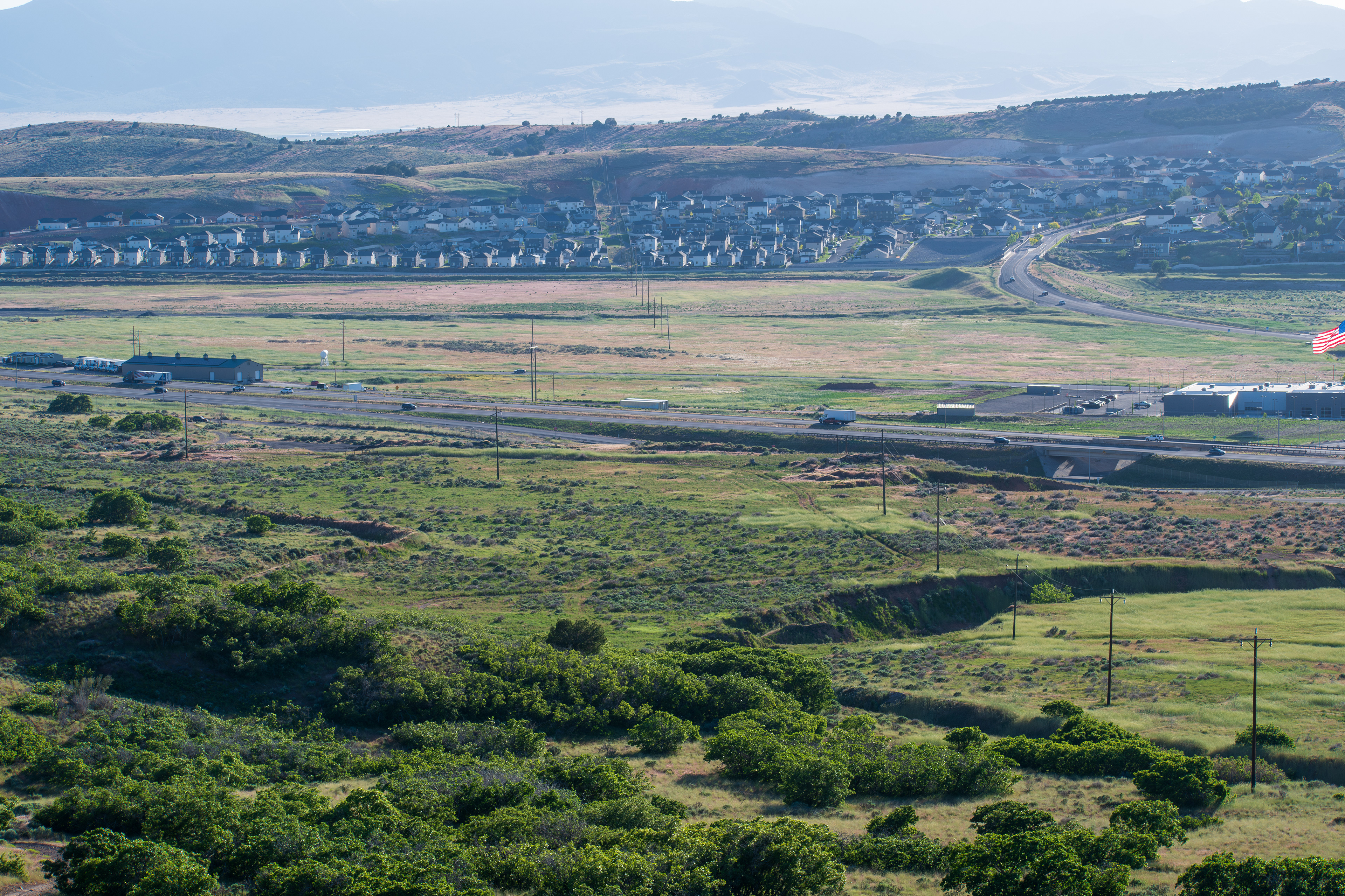 Santaquin, Utah – June 2, 2025: A distant view captures vehicles traveling along Interstate 15 as it winds through the valley near Santaquin, Utah, accompanied by power lines paralleling the roadway.