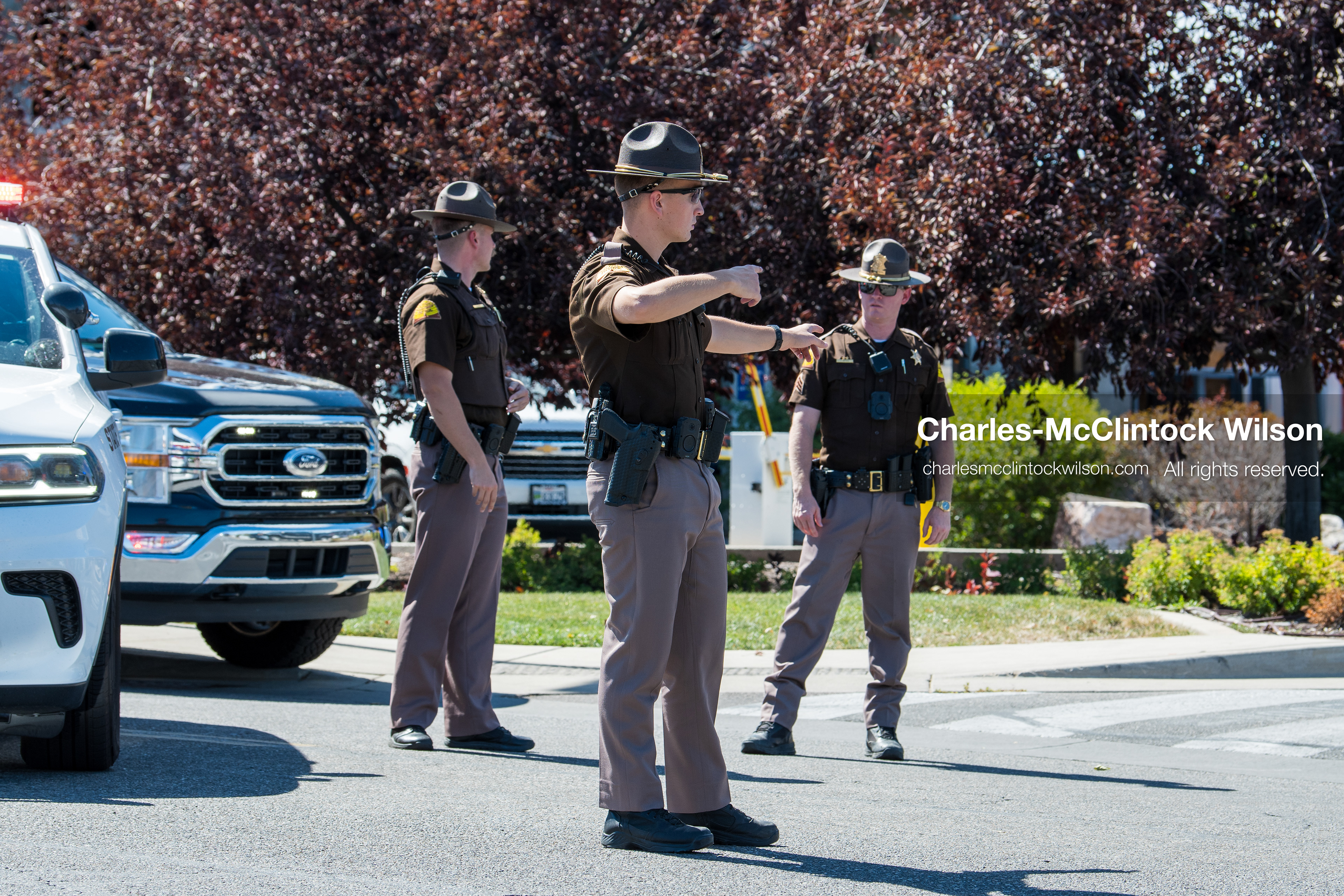 Utah Highway Patrol troopers point and direct individuals near a roadway checkpoint outside Intermountain Medical Center in Murray, Utah, United States, on August 17, 2026. Multiple regional police agencies secured the hospital perimeter as a safety precaution after shooting victims were admitted following a fatal shootout outside a funeral service in nearby Kearns. (Photo by Charles-McClintock Wilson/NurPhoto)