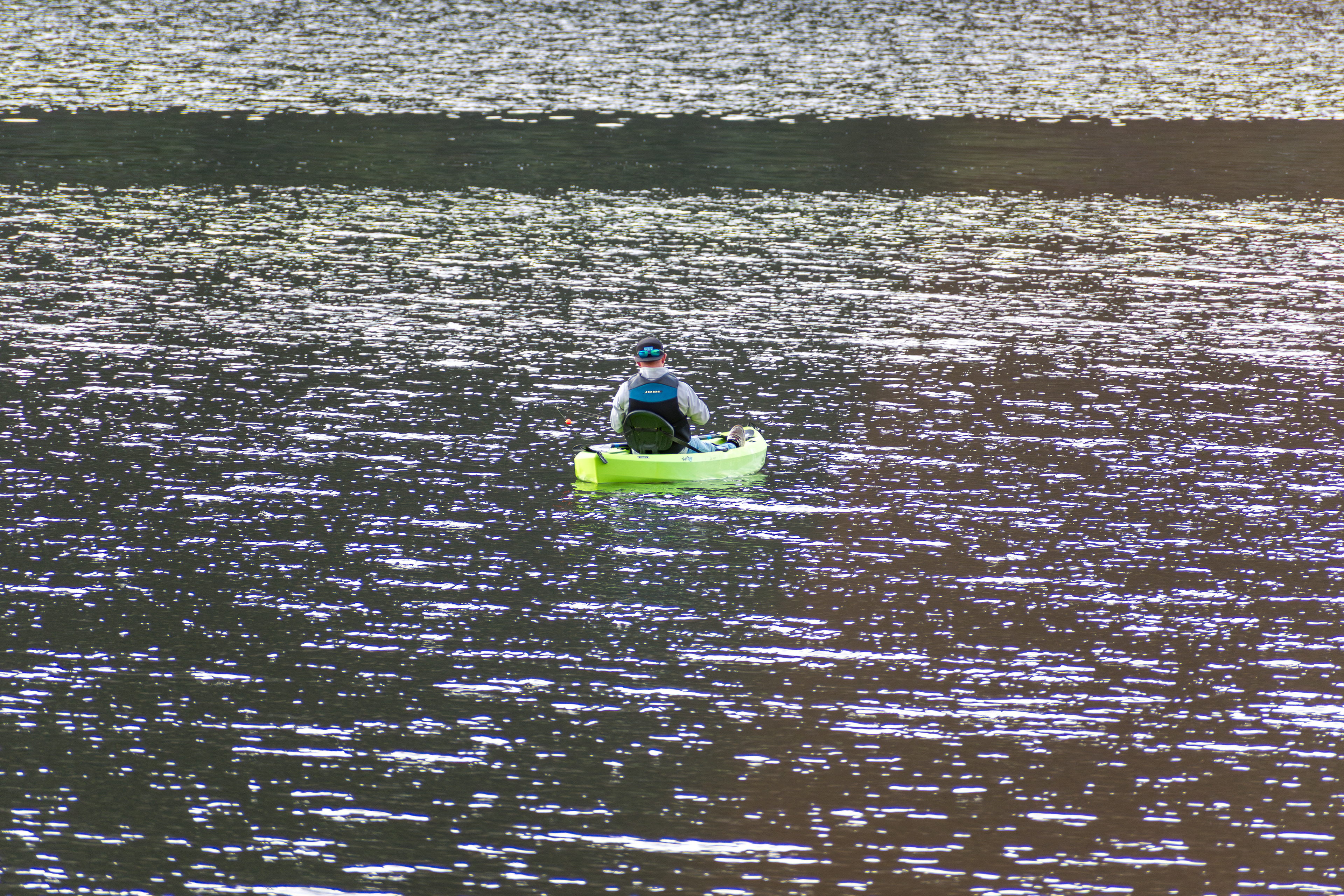 Summit County, Utah – July 20, 2025: A man paddles a bright green kayak while fishing at Smith and Morehouse Reservoir.