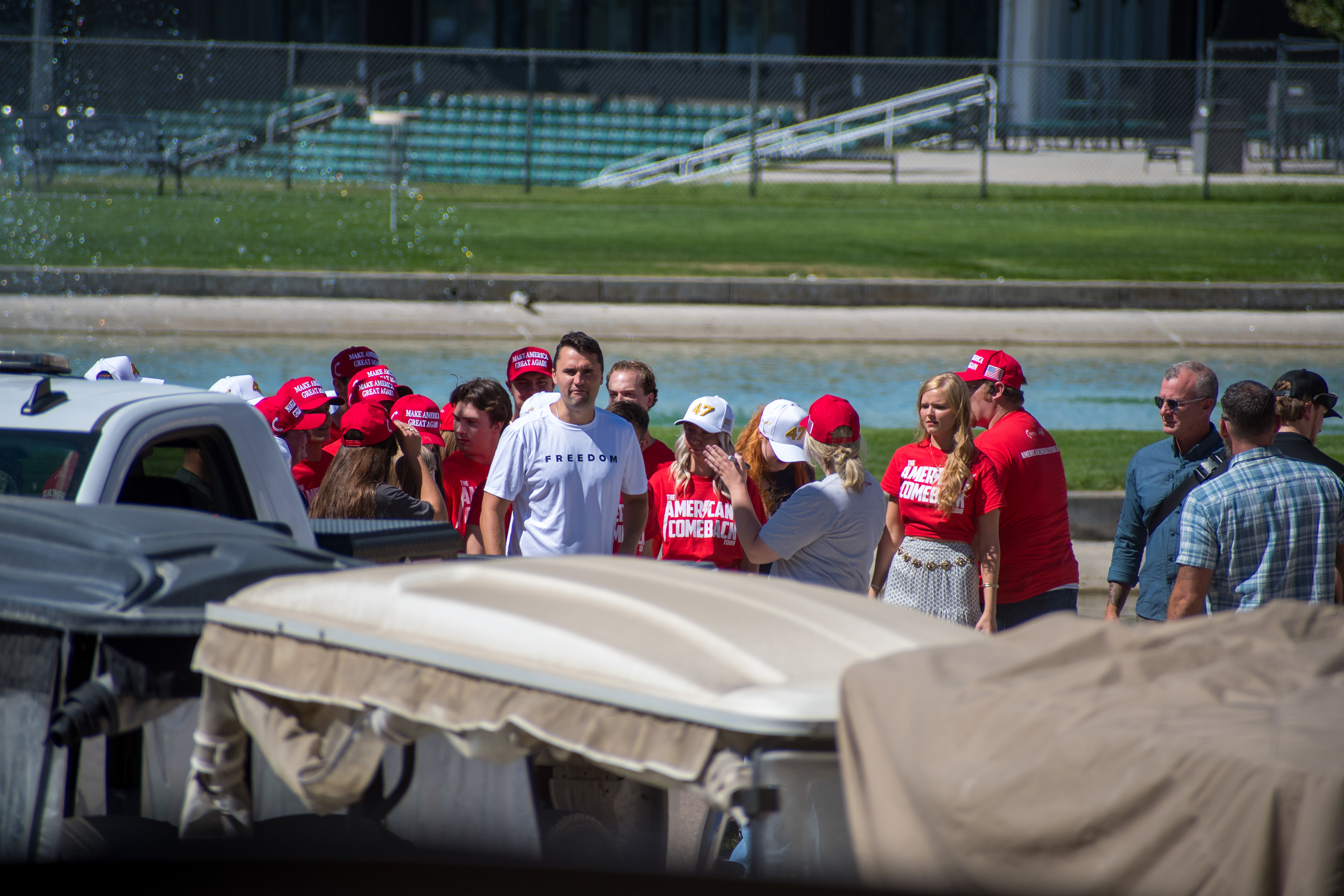 OREM, UTAH – SEPTEMBER 10, 2025: Supporters gather near a water feature ahead of Charlie Kirk’s public appearance at Utah Valley University. Wearing red shirts and hats bearing political slogans, attendees stand near event infrastructure and vehicles in anticipation of Kirk’s arrival. The image reflects the branding, energy, and grassroots mobilization that shaped the atmosphere leading into his final public engagement. © Charles-McClintock Wilson / ZUMA Press