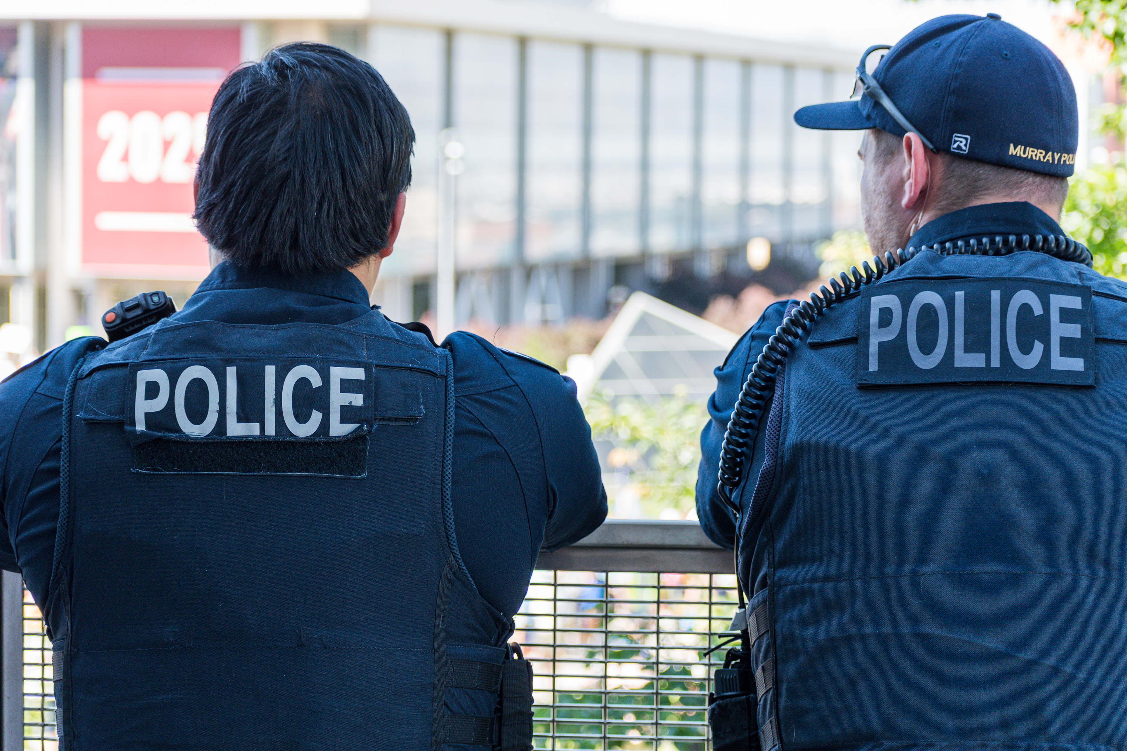 SALT LAKE CITY, UTAH – JUNE 15, 2025: Two police officers observe the crowd at the “No Kings” protest on the University of Utah campus, monitoring the demonstration for public safety.