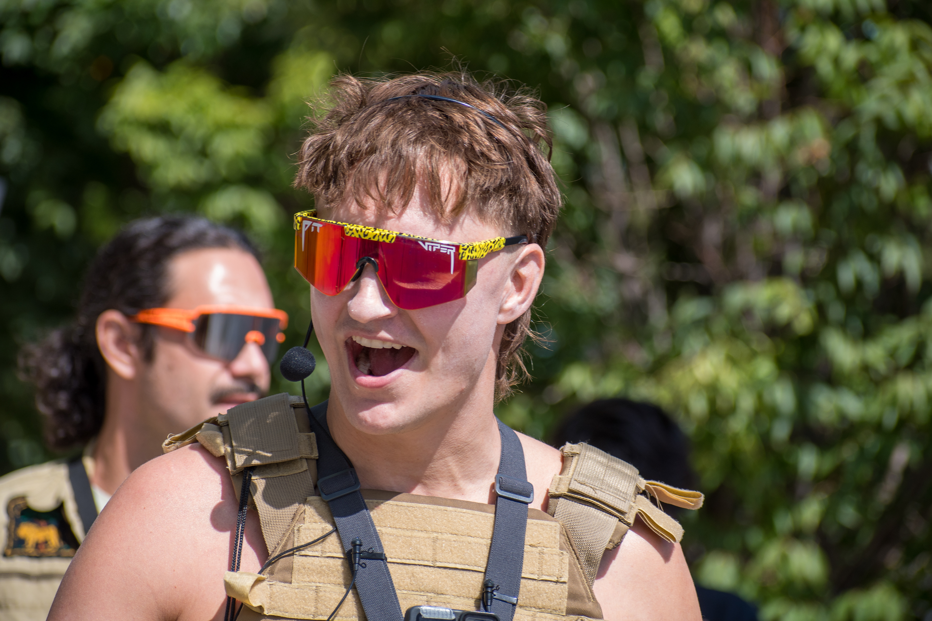 September 15, 2025 – Provo, Utah, United States: A demonstrator speaks emphatically into a headset microphone outside the Utah Valley Convention Center during a protest against the Department of Homeland Security career expo. Reflective “Pit Viper” sunglasses and a mullet hairstyle add visual intensity to the moment of civic expression. Photograph by Charles‑McClintock Wilson / ZUMA Press Wire