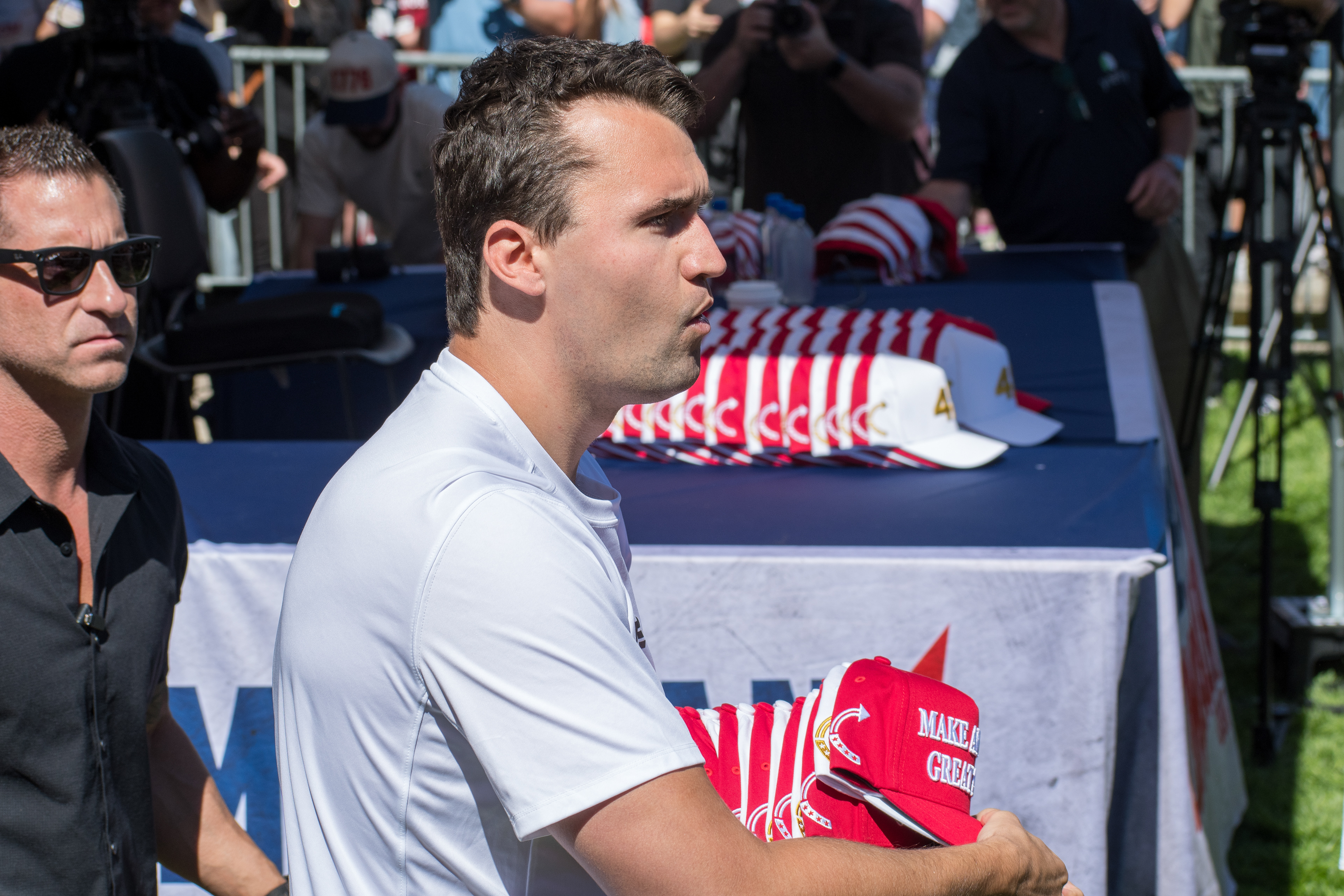 OREM, UTAH – SEPTEMBER 10, 2025: Charlie Kirk holds several “Make America Great Again” hats while interacting with supporters during a public event at Utah Valley University. Positioned near a merchandise table and surrounded by attendees, Kirk engages directly with the crowd in one of his final public moments. The image reflects the branding, outreach, and political symbolism that defined the gathering. © Charles-McClintock Wilson / ZUMA Press 