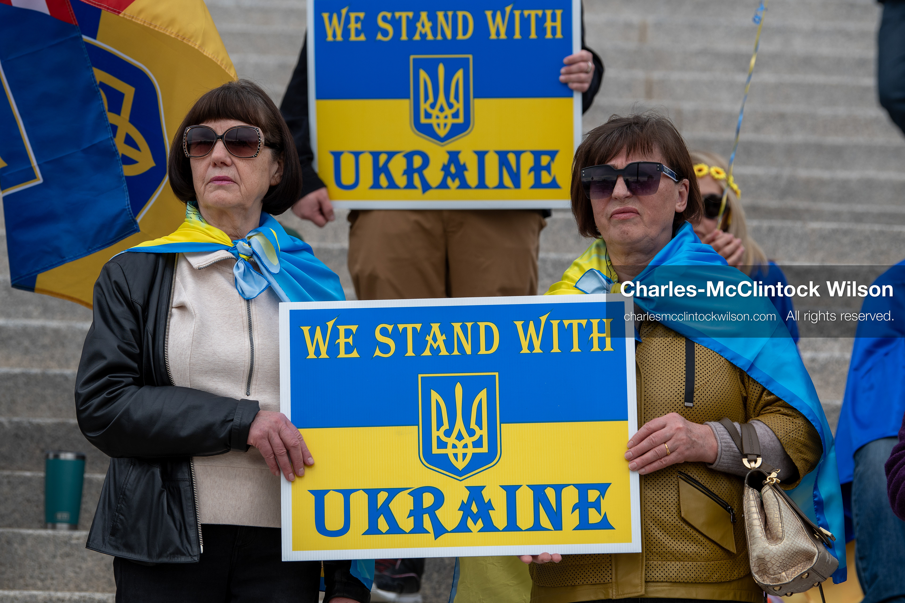  February 28, 2026, Salt Lake City, Utah, USA: Demonstrators hold signs reading We Stand With Ukraine while wrapped in the Ukrainian flag during the Stand With Ukraine rally at the Utah State Capitol. The gathering marked the four year anniversary of the full scale Russian invasion of Ukraine and brought community members together in support of Ukrainians and local humanitarian efforts. (Credit Image: © Charles McClintock Wilson/ZUMA Press Wire)