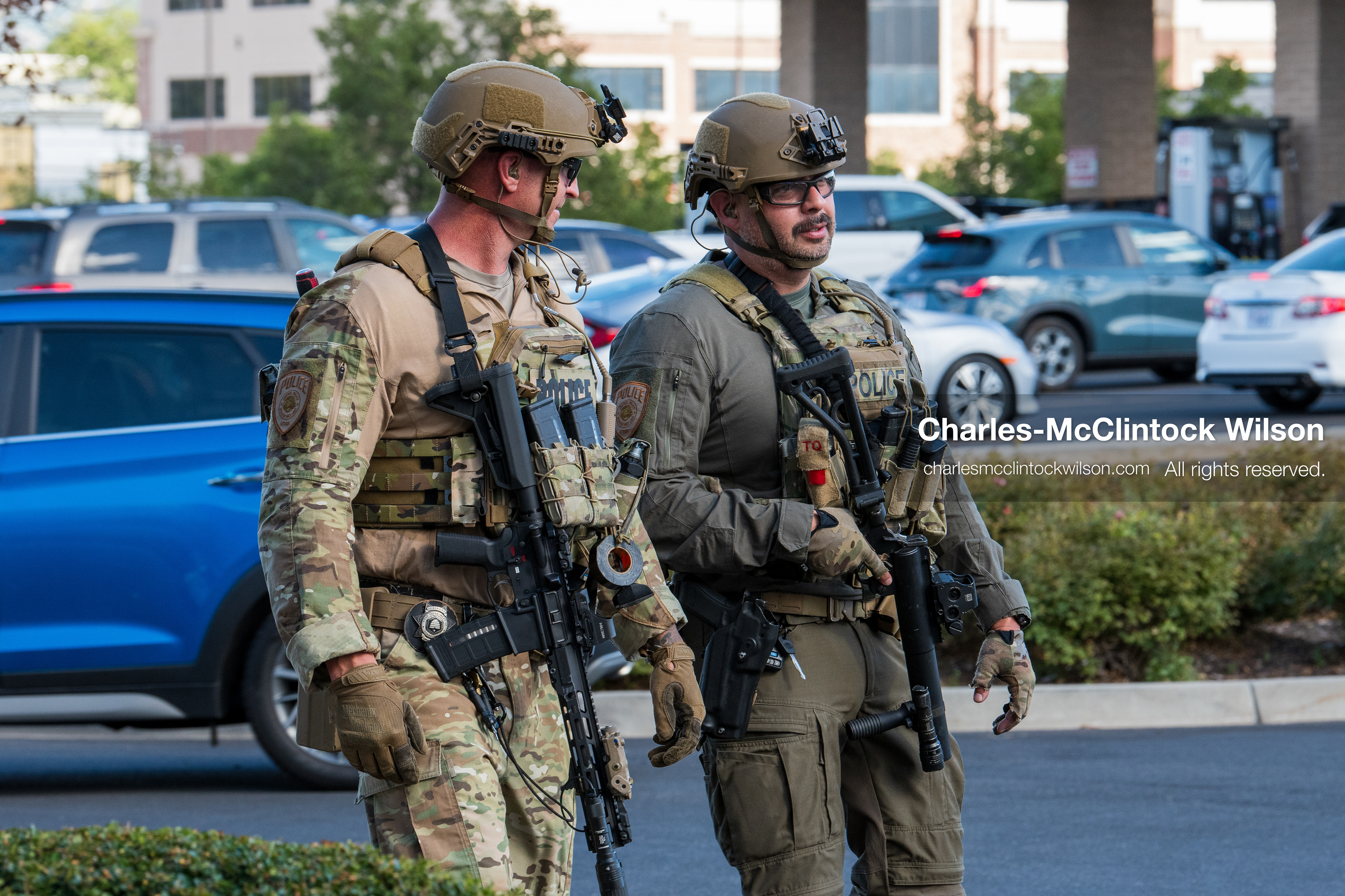 Two armed law enforcement officers in tactical gear and helmets patrol the parking area outside Intermountain Medical Center in Murray, Utah, United States, on August 17, 2026. Multiple regional police agencies secured the hospital perimeter as a safety precaution after shooting victims were admitted following a fatal shootout outside a funeral service in nearby Kearns. (Photo by Charles-McClintock Wilson/NurPhoto)