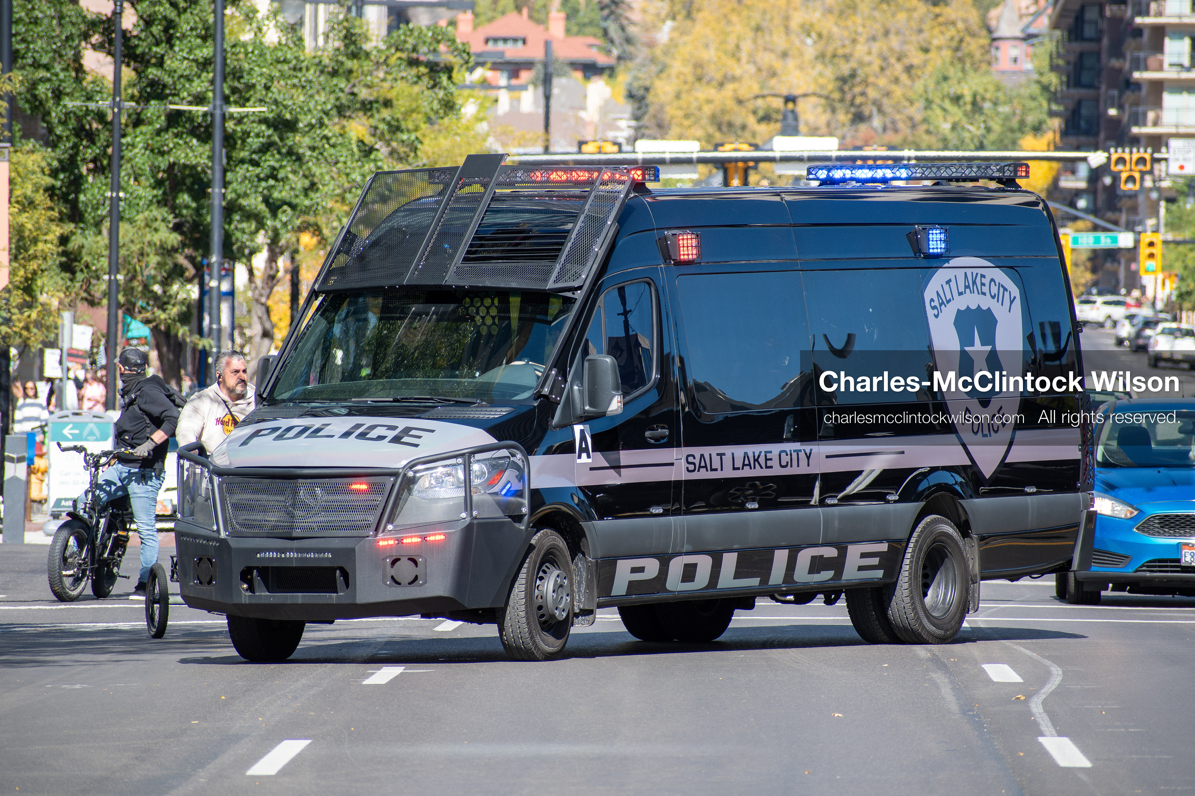 October 18, 2025, Salt Lake City, Utah, USA: A police van drives past demonstrators during a "No Kings" protest on 14th Street in Salt Lake City, Utah. The protest was part of a nationwide mobilization.