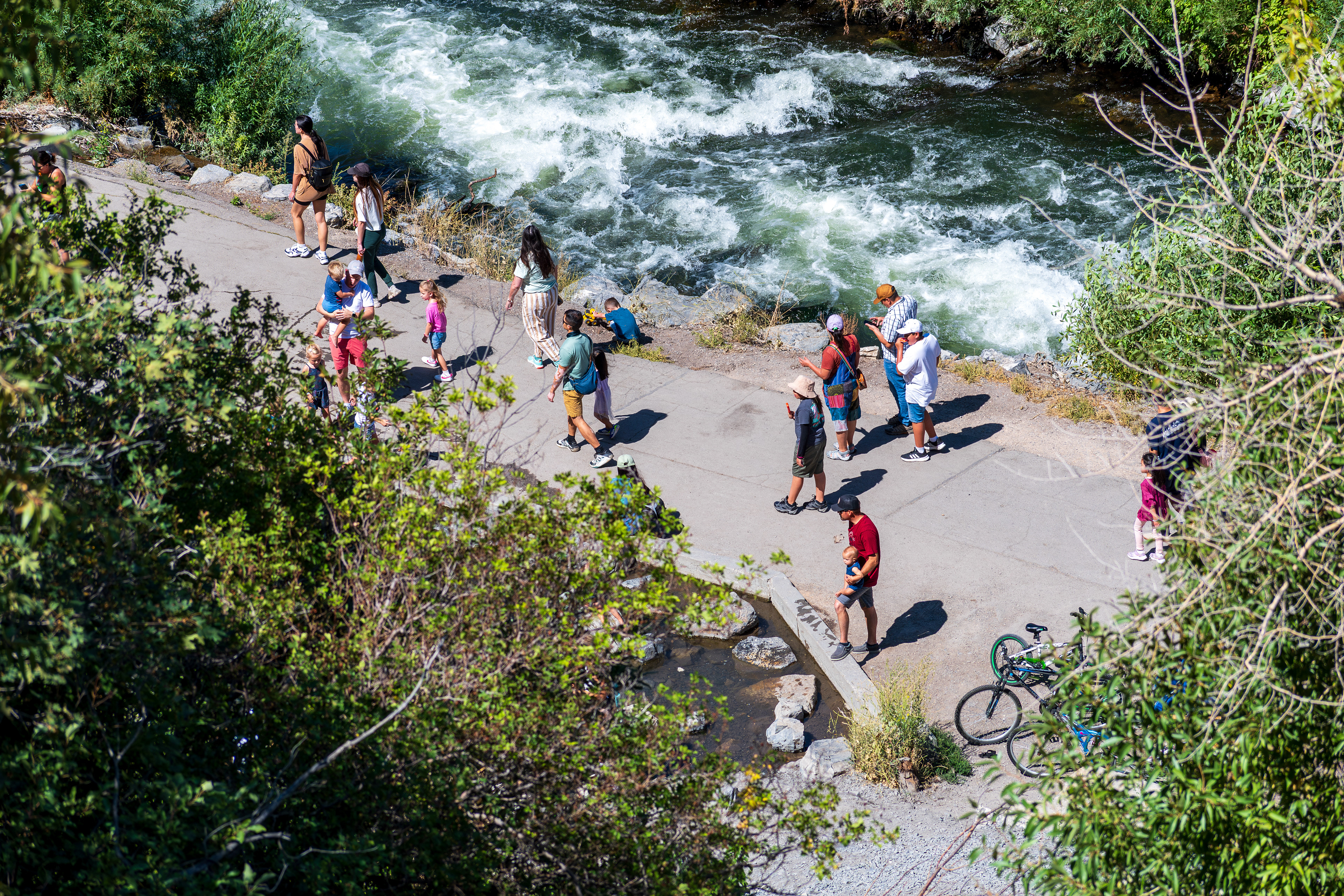 Provo Canyon, Utah, USA — September 1, 2025: Cyclists and pedestrians gather near the fast-flowing Provo River, moving along a paved path that traces the canyon’s natural contours. 