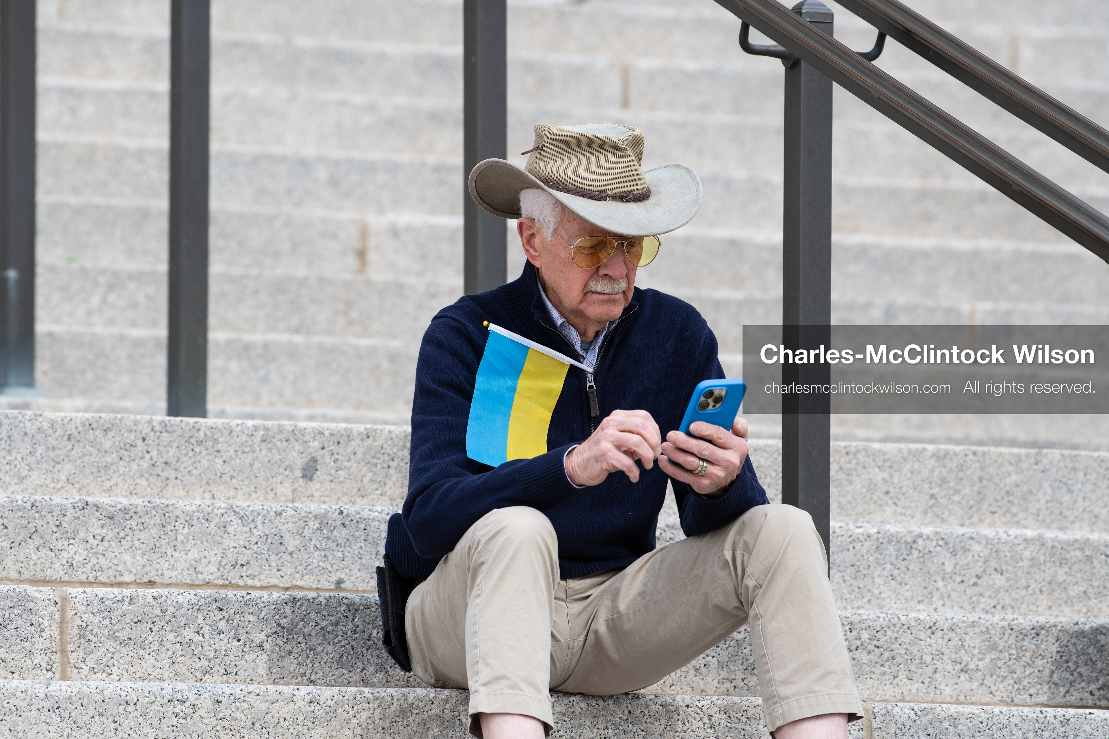 February 28, 2026, Salt Lake City, Utah, USA: An demonstrator sits on the steps near the Utah State Capitol with a small Ukrainian flag tucked into a jacket during the Stand With Ukraine rally. The gathering marked the four year anniversary of the full scale Russian invasion of Ukraine and brought community members together in support of Ukrainians and local humanitarian efforts. (Credit Image: © Charles McClintock Wilson/ZUMA Press Wire)