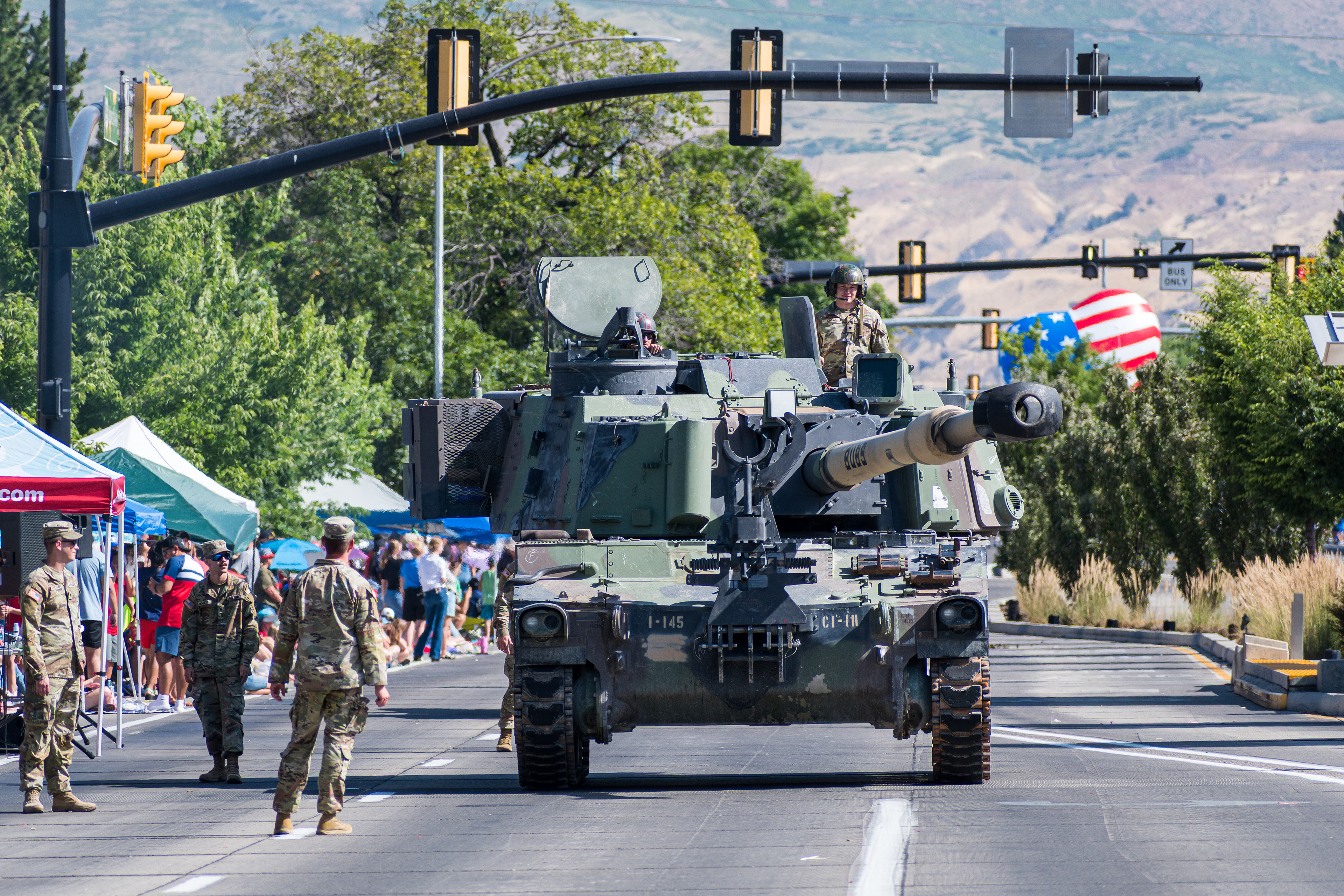 Provo, Utah – July 4, 2025: U.S. Army personnel ride atop a tank as others march beside it during the Freedom Festival Grand Parade in downtown Provo.
