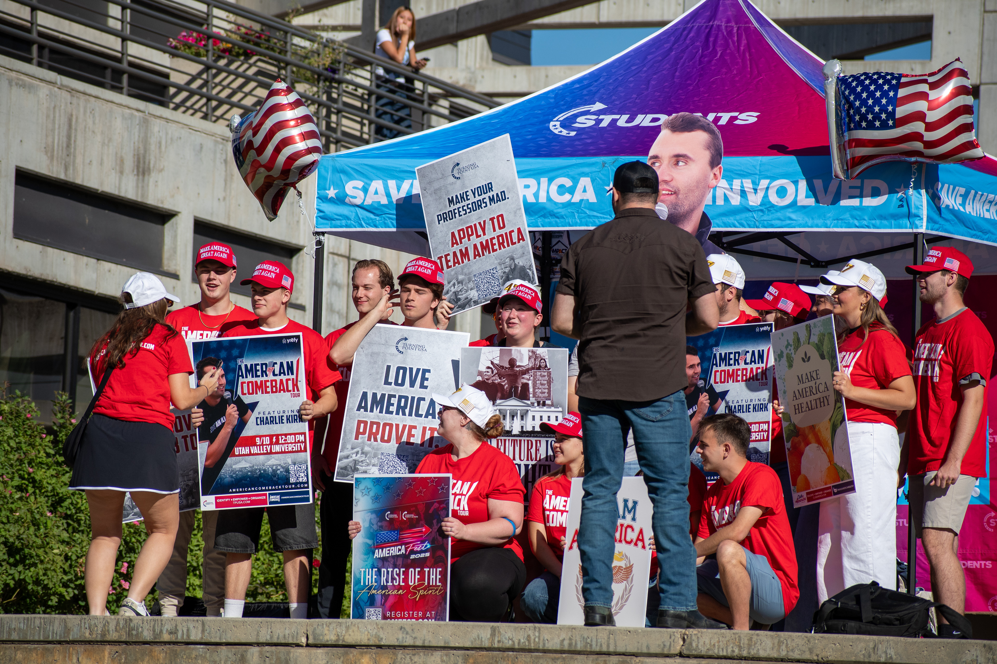 OREM, UTAH – SEPTEMBER 10, 2025: Attendees gather outside the Pope Science building at Utah Valley University during the opening stop of the American Comeback Tour. Surrounded by signage and coordinated attire, the group reflects a moment of thematic clarity, civic invitation, and communal energy. The image captures the rhythm of participation and the visual texture that shaped the event’s atmosphere. © Charles-McClintock Wilson / ZUMA Press
