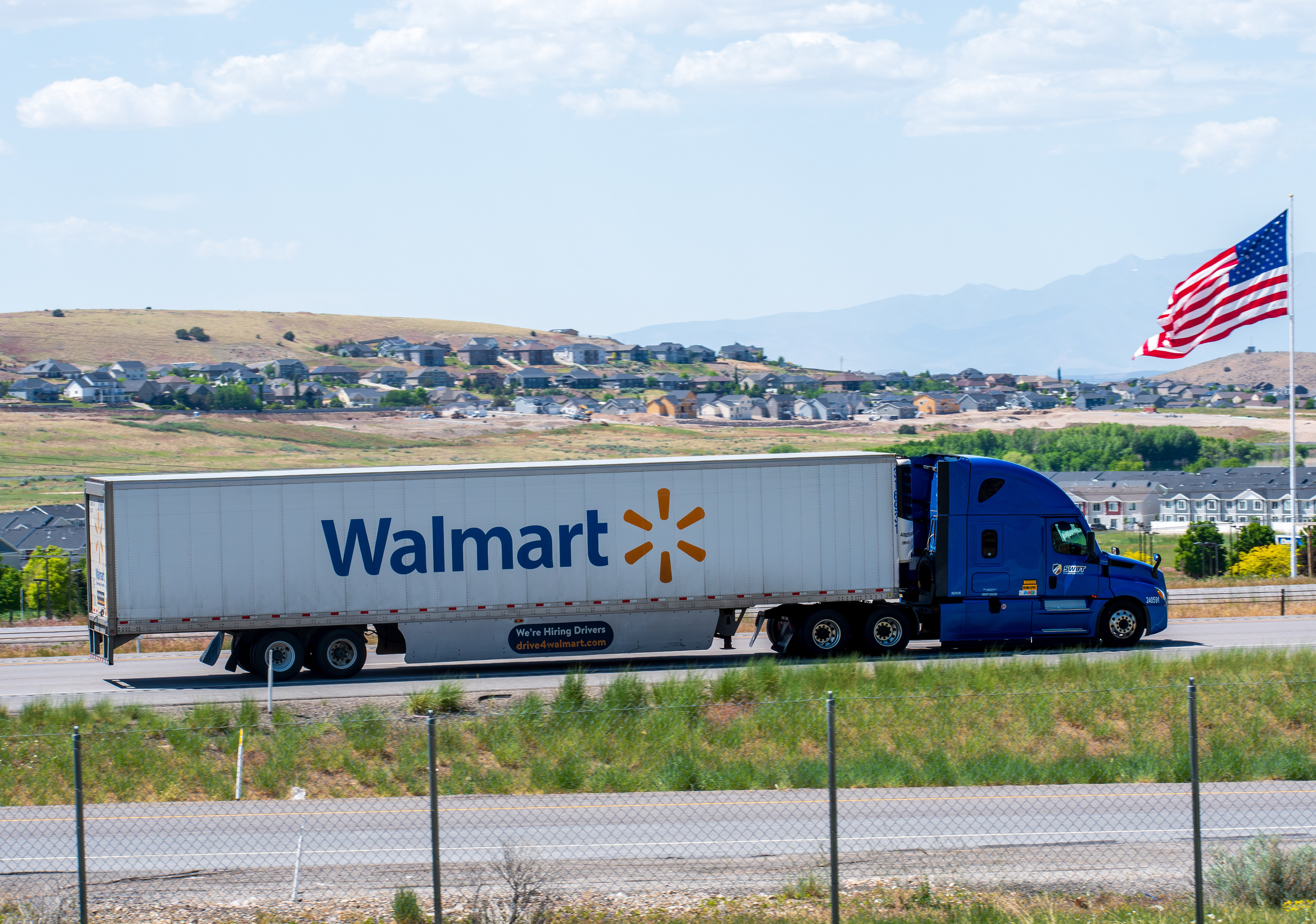 Santaquin, Utah – June 2, 2025: A Walmart trailer travels northbound on Interstate 15 past an American flag in Santaquin, Utah, United States.