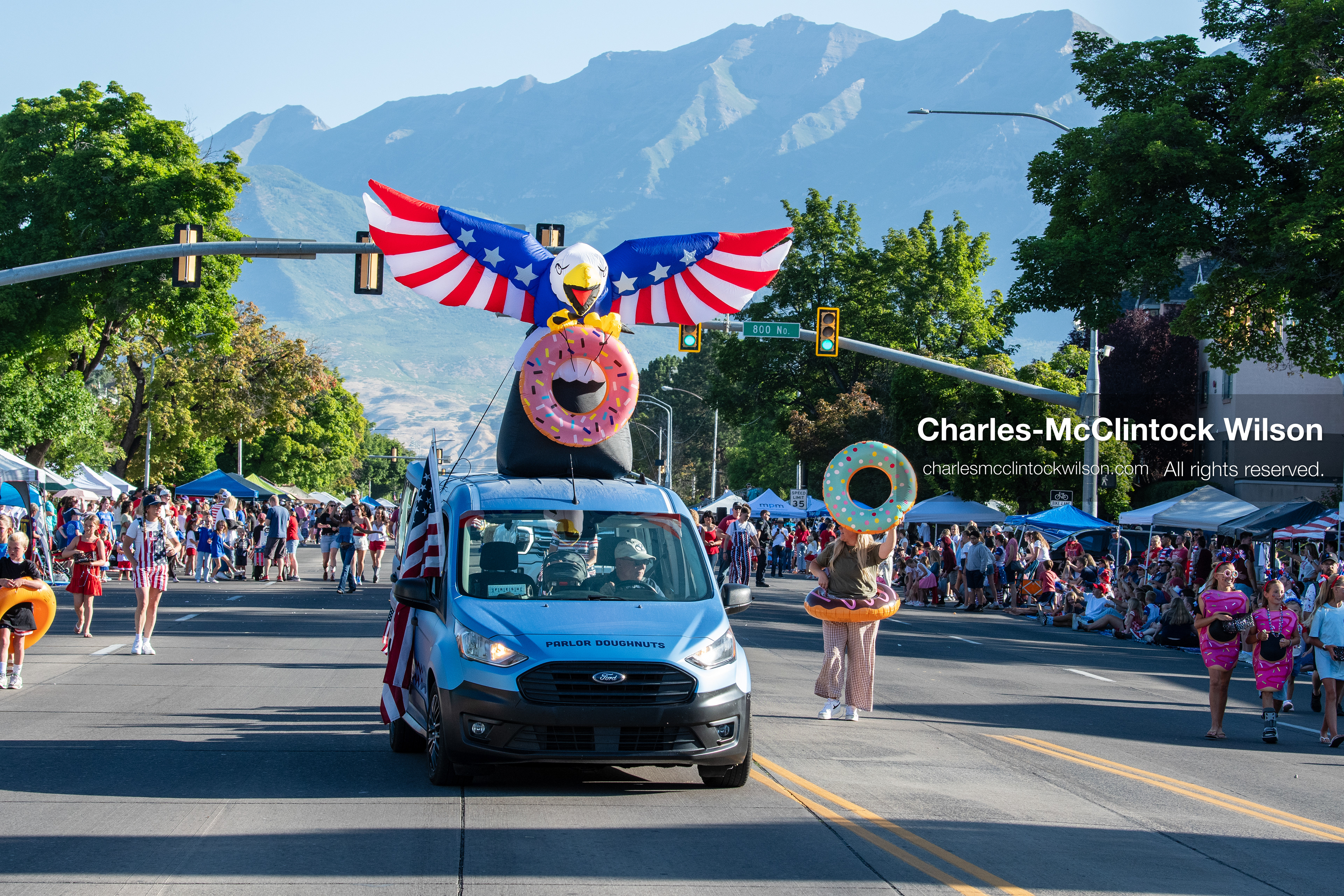July 4, 2026, Provo, Utah, USA: A utility van carrying a large inflatable patriotic eagle holding a pink donut drives down the street beside a participant wearing a giant mint donut pool float during America's Freedom Festival Grand Parade in Provo, Utah, Saturday, July 4, 2026. The annual Independence Day event features expanded programming to honor the 250th anniversary of United States independence. (Credit Image: © Charles-McClintock Wilson/ZUMA Press Wire)