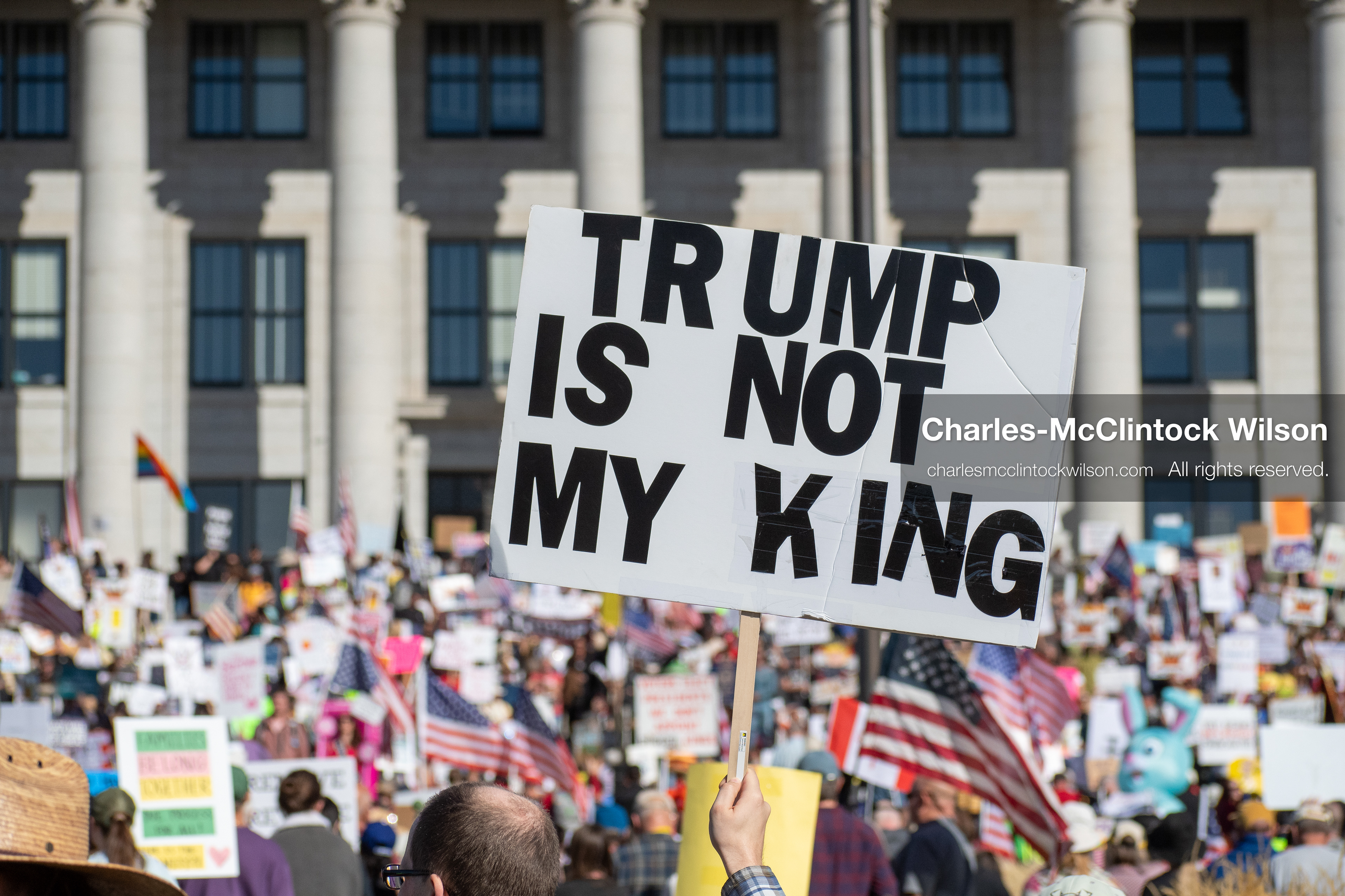 October 18, 2025, Salt Lake City, Utah, USA: A demonstrator raises a placard during a "No Kings" protest held at the Utah State Capitol. Other participants and signs are visible in the background during the public gathering.