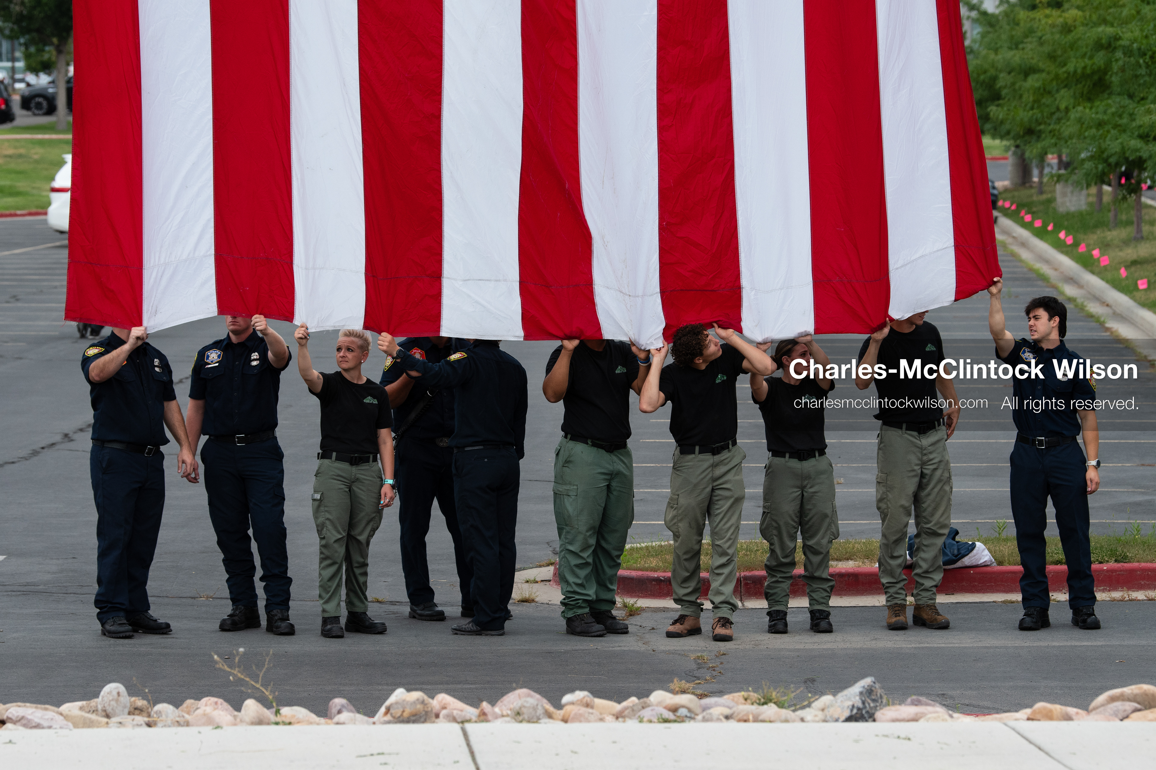 First responders stand in a row holding the bottom edge of a large American flag outside the UCCU Center at Utah Valley University in Orem, Utah, on Wednesday, July 29, 2026. More than 300 people came to the public memorial ceremony to honor Provo Fire Captain Spencer Long, his wife Katrina, and three of their sons, who died after a flash flood hit their campsite near the Sunglow Campground in Wayne County. (Photo by Charles-McClintock Wilson/Sipa USA)