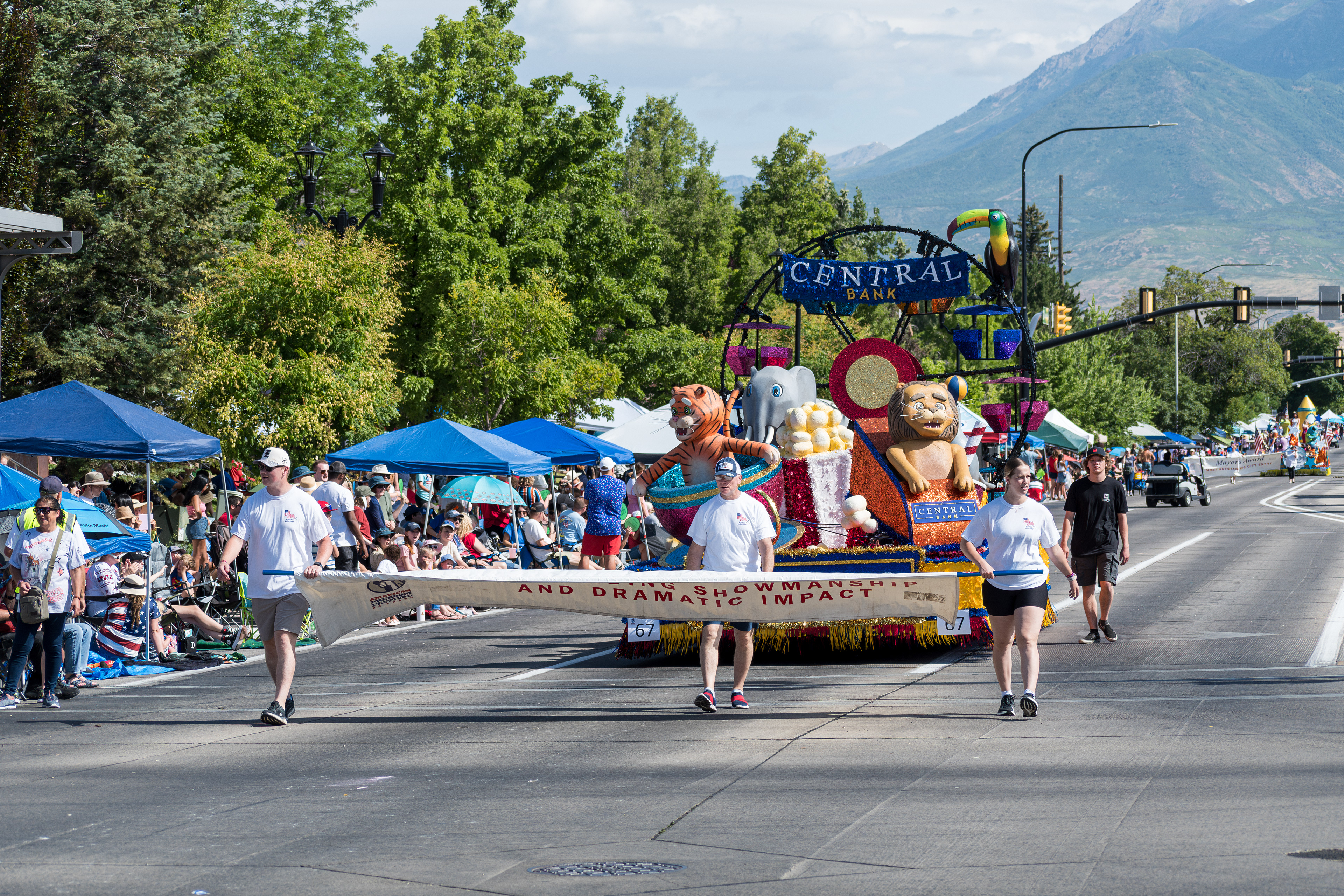 Provo, Utah – July 4, 2025: Participants carry a banner as a decorated float follows during the Freedom Festival Grand Parade in downtown Provo.