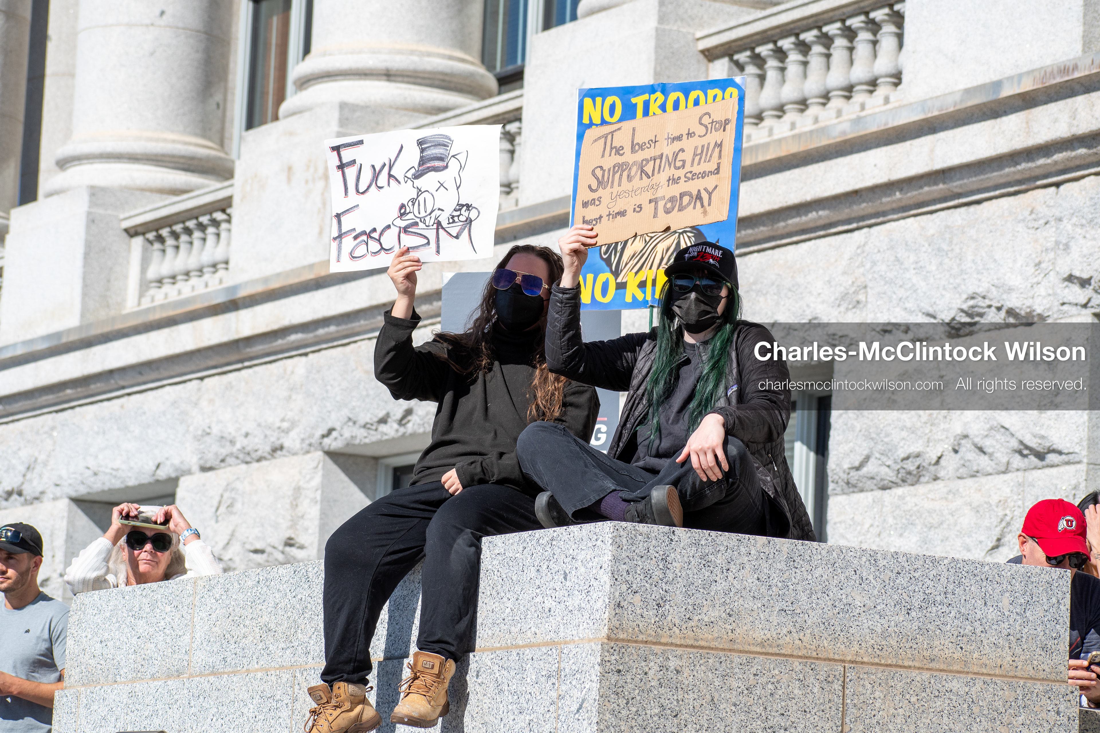 October 18, 2025, Salt Lake City, Utah, USA: Demonstrators sit on a stone ledge during a "No Kings" protest at the Utah State Capitol. The protest was part of a nationwide mobilization.