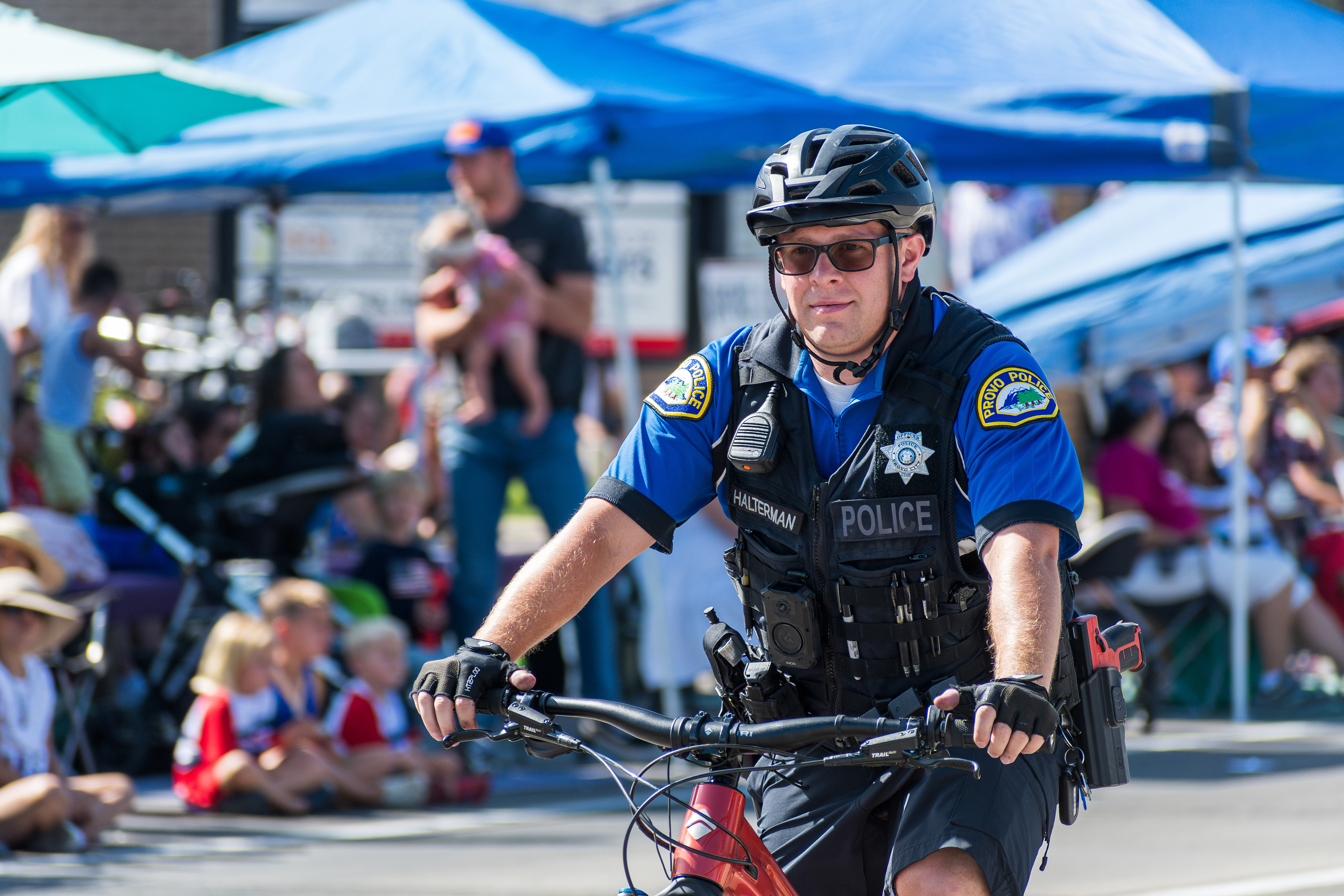 Provo, Utah – July 4, 2025: A police officer rides a bicycle along the parade route during the Freedom Festival Grand Parade, providing security and engaging with the community.