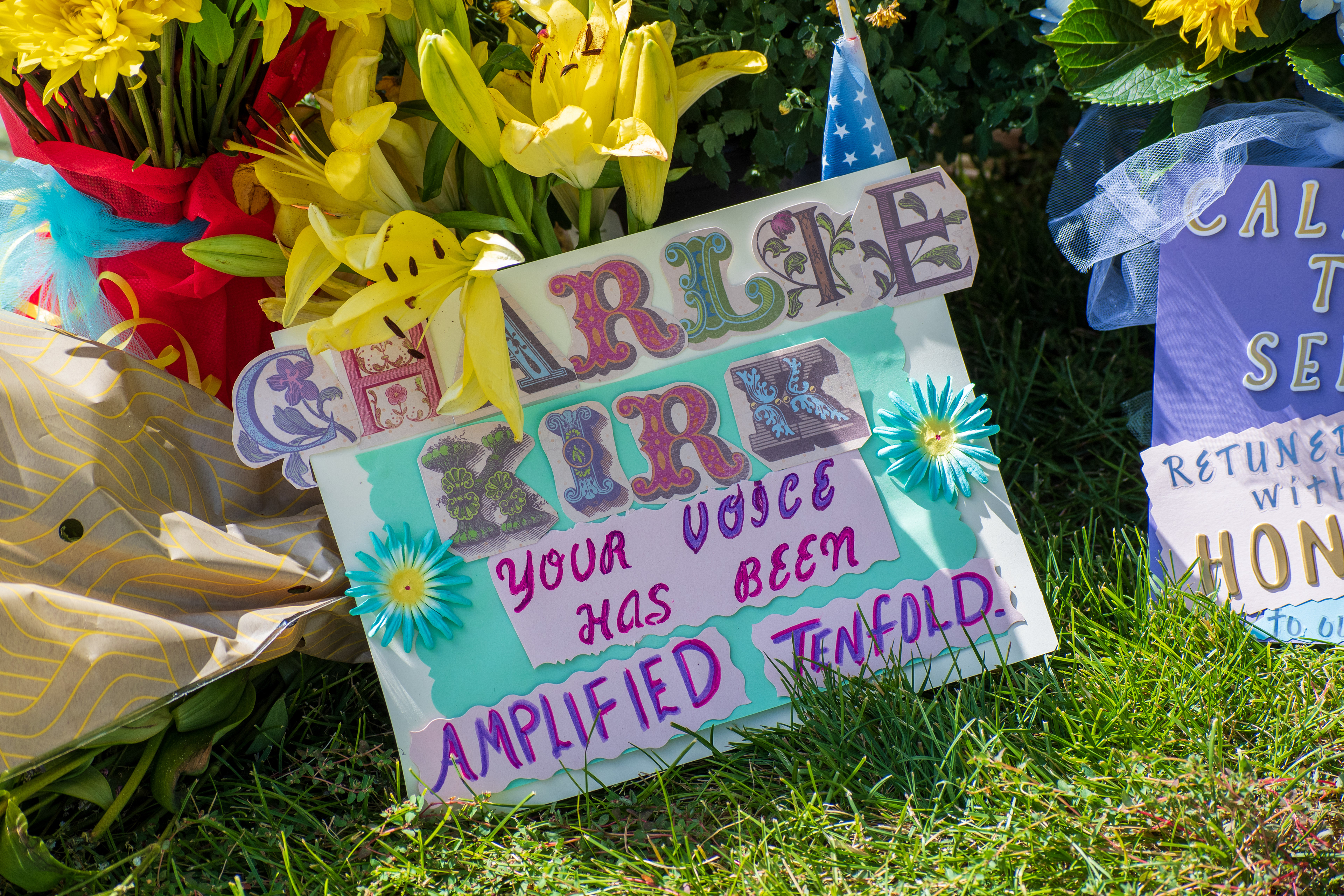 OREM, UTAH – SEPTEMBER 12, 2025: A tribute display for Charlie Kirk features colorful signs reading “CHARLIE BIRD – YOUR VOICE HAS BEEN AMPLIFIED TENFOLD” and “CALL TO SERVE RETURNED WITH HONOR,” surrounded by blue and yellow paper flowers. The memorial near Utah Valley University reflects a vibrant gesture of remembrance and celebration. © Charles‑McClintock Wilson / ZUMA Press