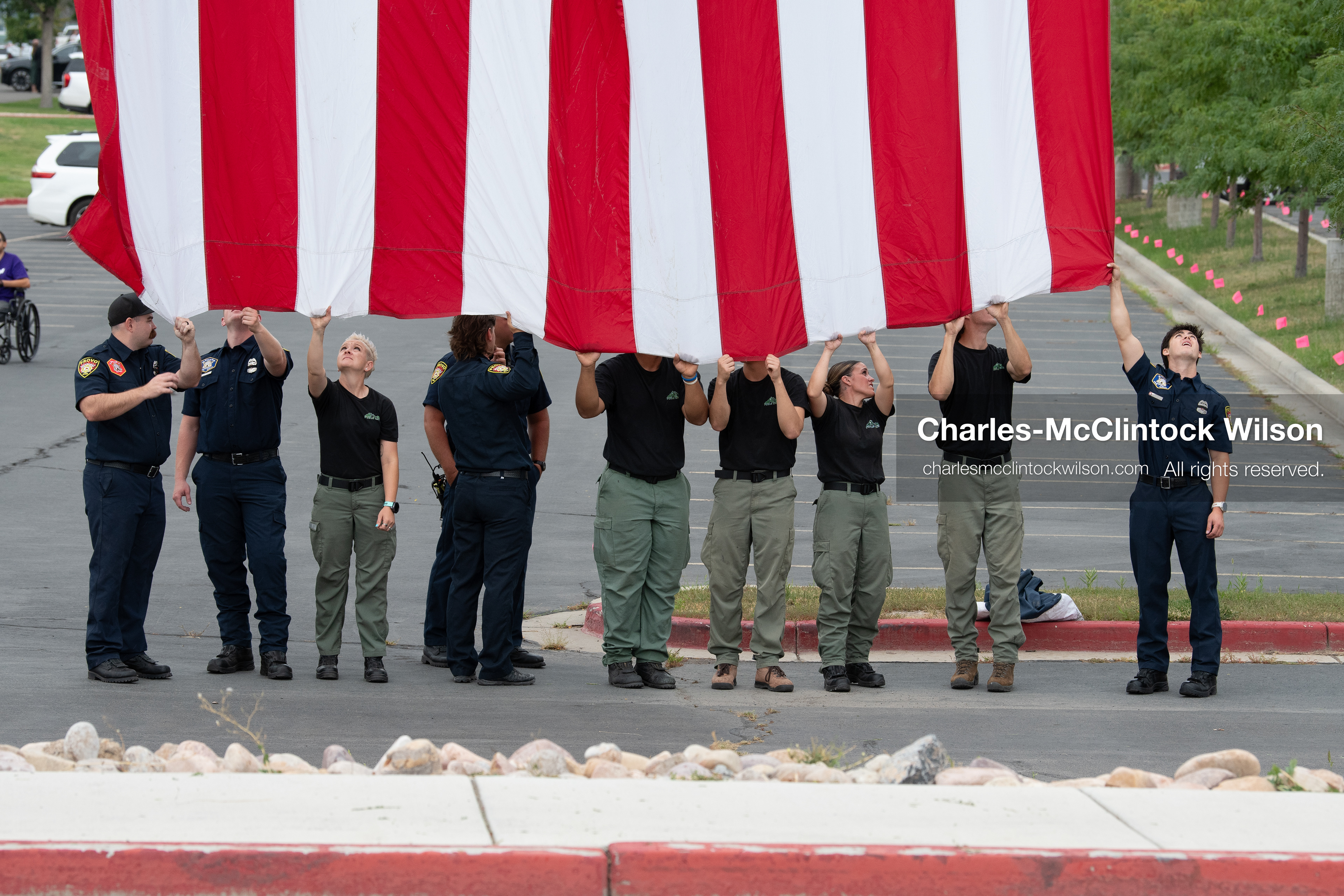 First responders stand in a row holding the bottom edge of a large American flag outside the UCCU Center at Utah Valley University in Orem, Utah, on Wednesday, July 29, 2026. More than 300 people came to the public memorial ceremony to honor Provo Fire Captain Spencer Long, his wife Katrina, and three of their sons, who died after a flash flood hit their campsite near the Sunglow Campground in Wayne County. (Photo by Charles-McClintock Wilson/Sipa USA)