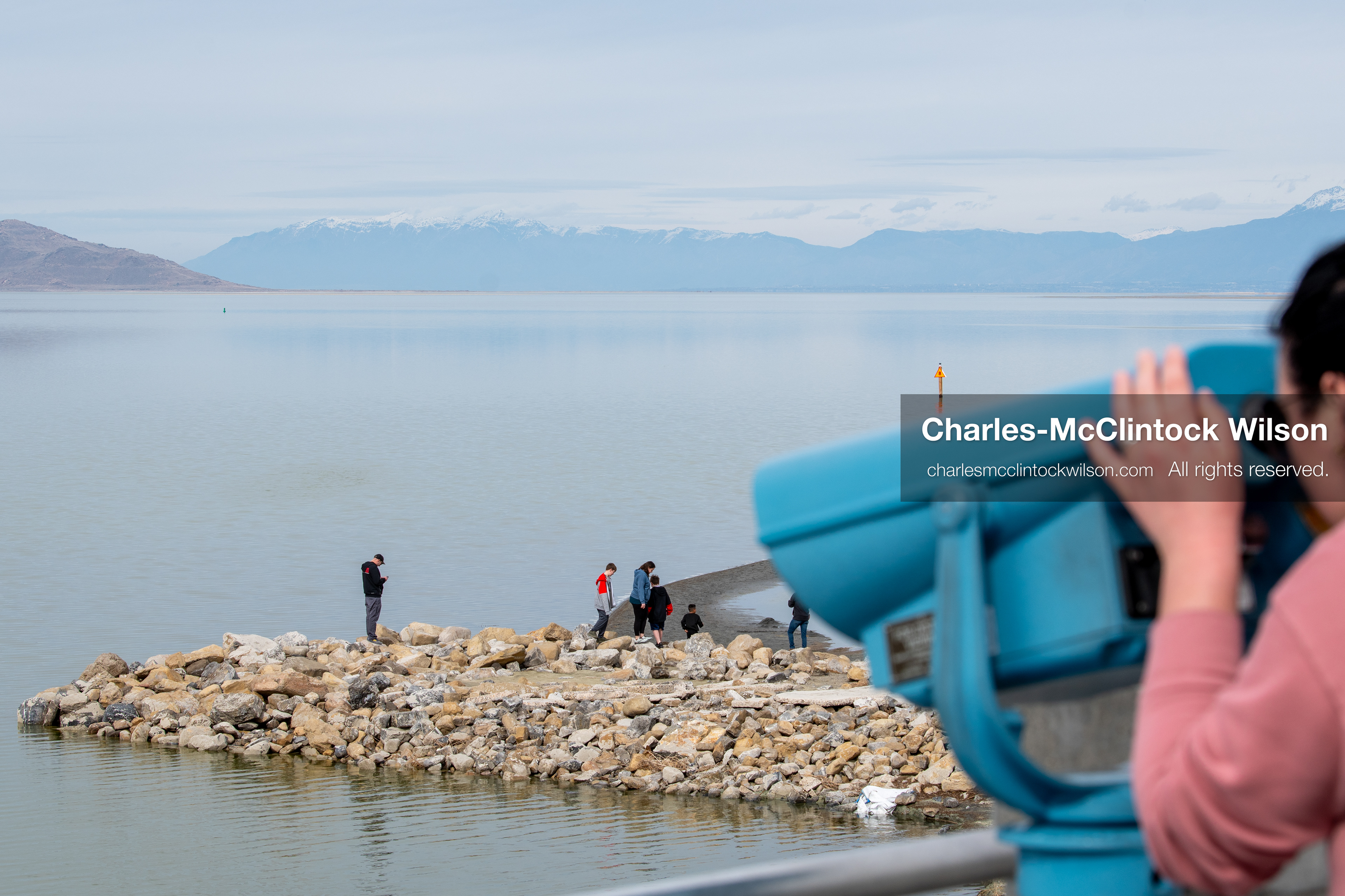 March 1, 2026, Great Salt Lake, Utah, USA: A person looks through a viewer toward the Great Salt Lake as others stand on a rocky jetty in the distance. The region continues to experience historically low water levels. Reports from state officials and the Great Salt Lake Strike Team state that the lake remains in a serious adverse‑effects range, with elevations among the lowest recorded in more than one hundred years. The lake has drawn increased public attention as lawmakers consider large‑scale water projects and long‑term plans to address declining conditions. (Credit Image: © Charles‑McClintock Wilson/ZUMA Press Wire)