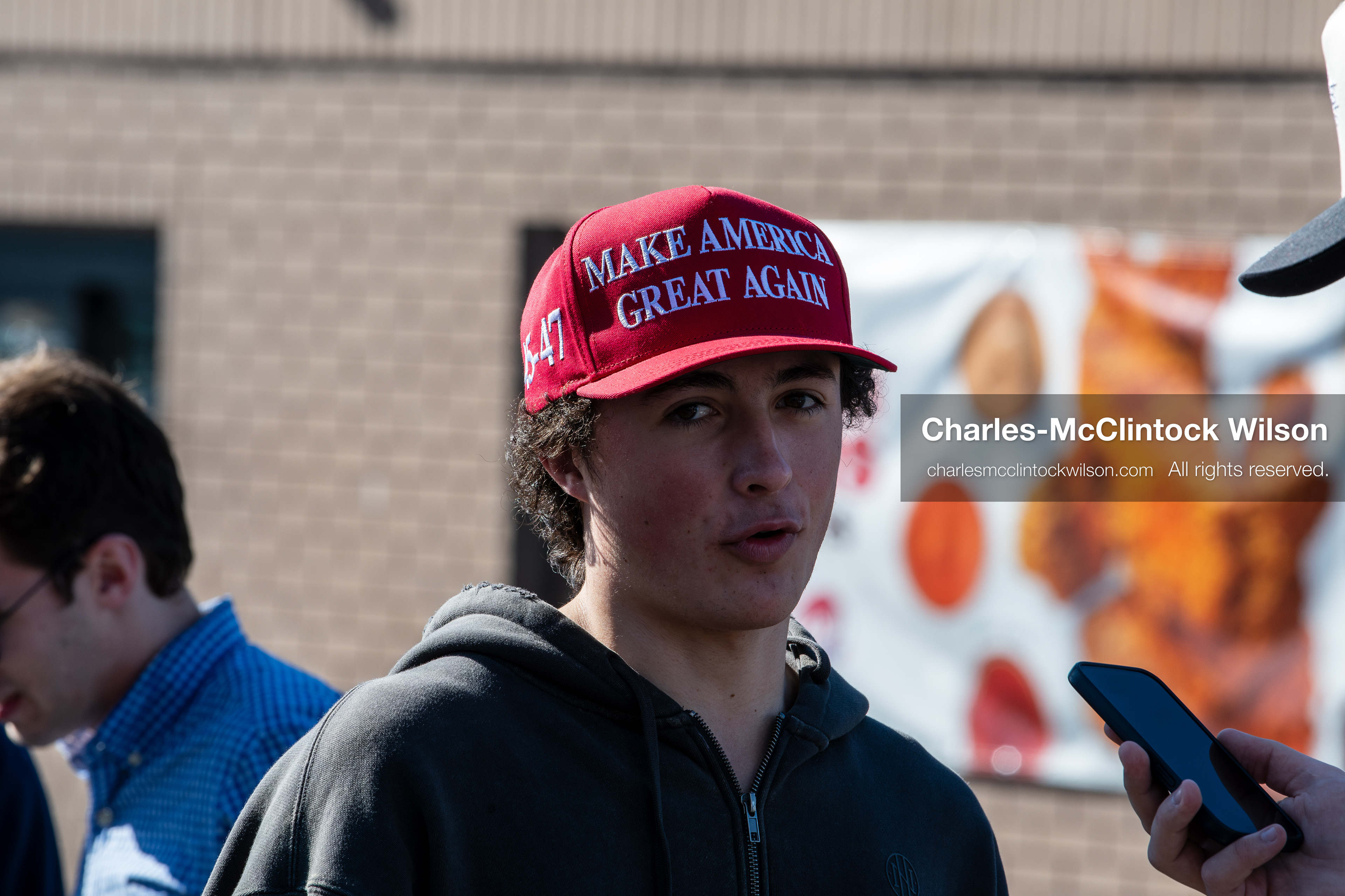 February 5, 2026, Provo, Utah, USA: A person wearing a red Make America Great Again hat is interviewed by another individual outside a business near Brigham Young University in Provo during a gathering opposing the presence of US Customs and Border Protection recruiters at a career fair held on the BYU campus. (Credit Image: © Charles McClintock Wilson/ZUMA Press Wire)
