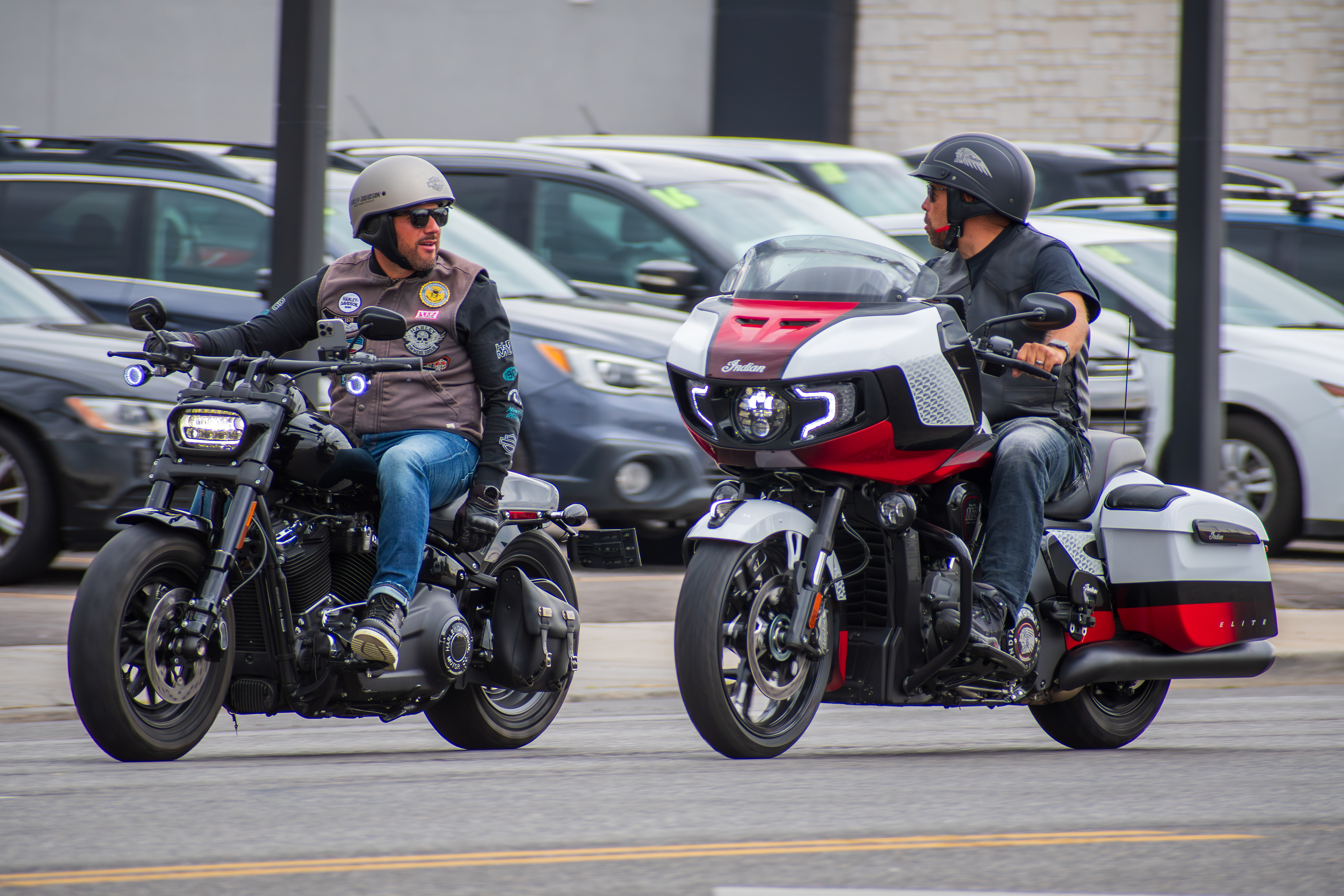 Murray, Utah — Sept. 8, 2025: Two motorcyclists pause for a roadside exchange on separate bikes, one outfitted with touring gear and red trim.