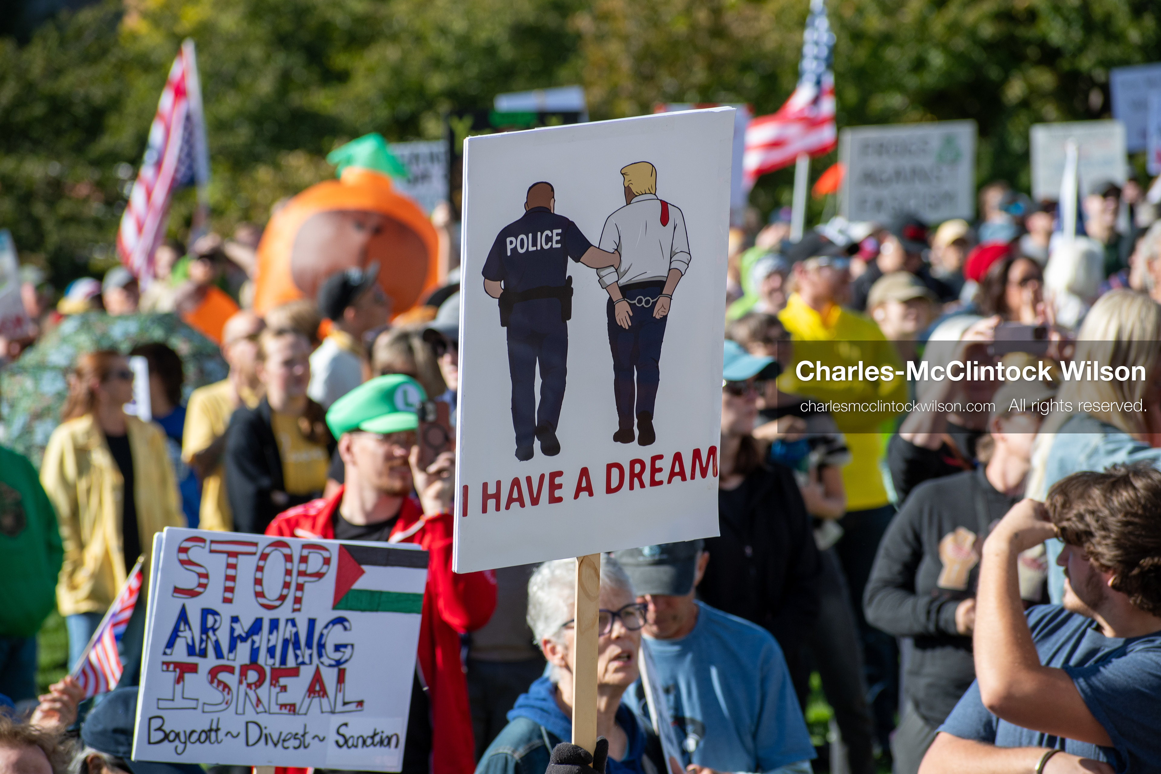 October 18, 2025, Salt Lake City, Utah, USA: A demonstrator raises a placard during a "No Kings" protest held at the Utah State Capitol. Other participants and signs are visible in the background during the public gathering.