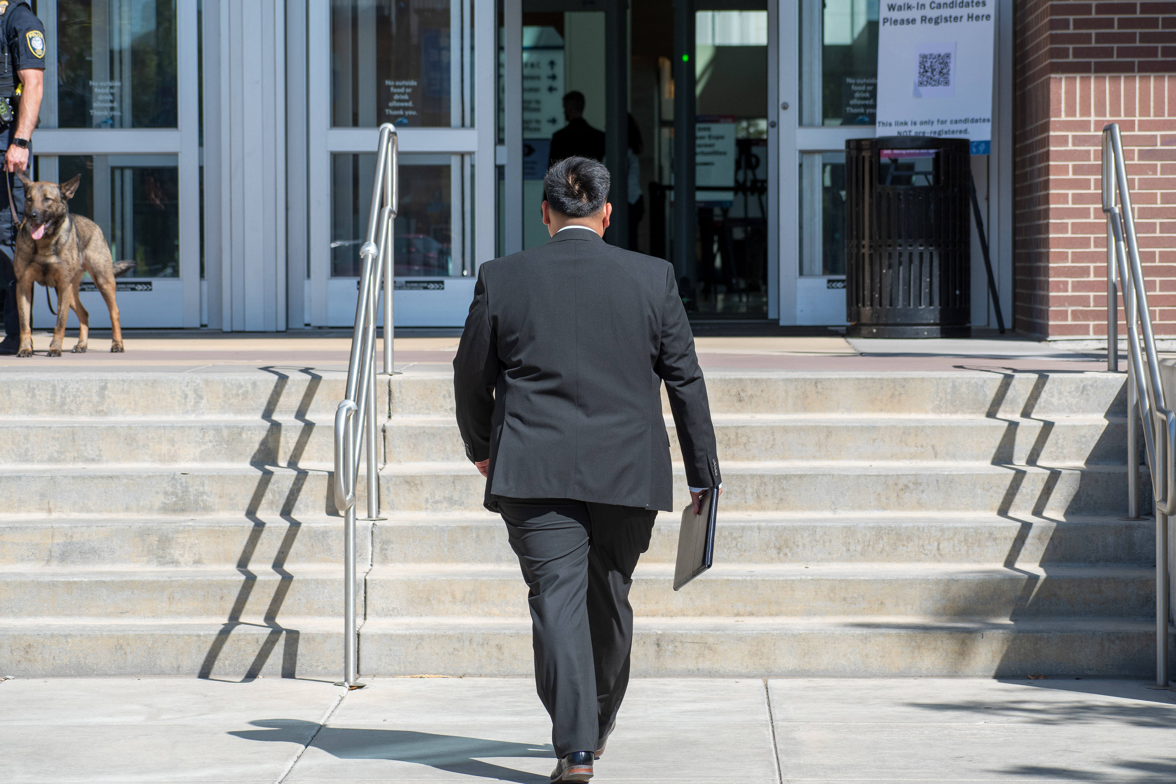 September 15, 2025 – Provo, Utah, United States: A man in formal attire walks toward the entrance of the Utah Valley Convention Center during the Department of Homeland Security career expo. A police officer and K-9 unit stand nearby as security measures accompany federal recruitment efforts. Photograph by Charles‑McClintock Wilson / ZUMA Press Wire