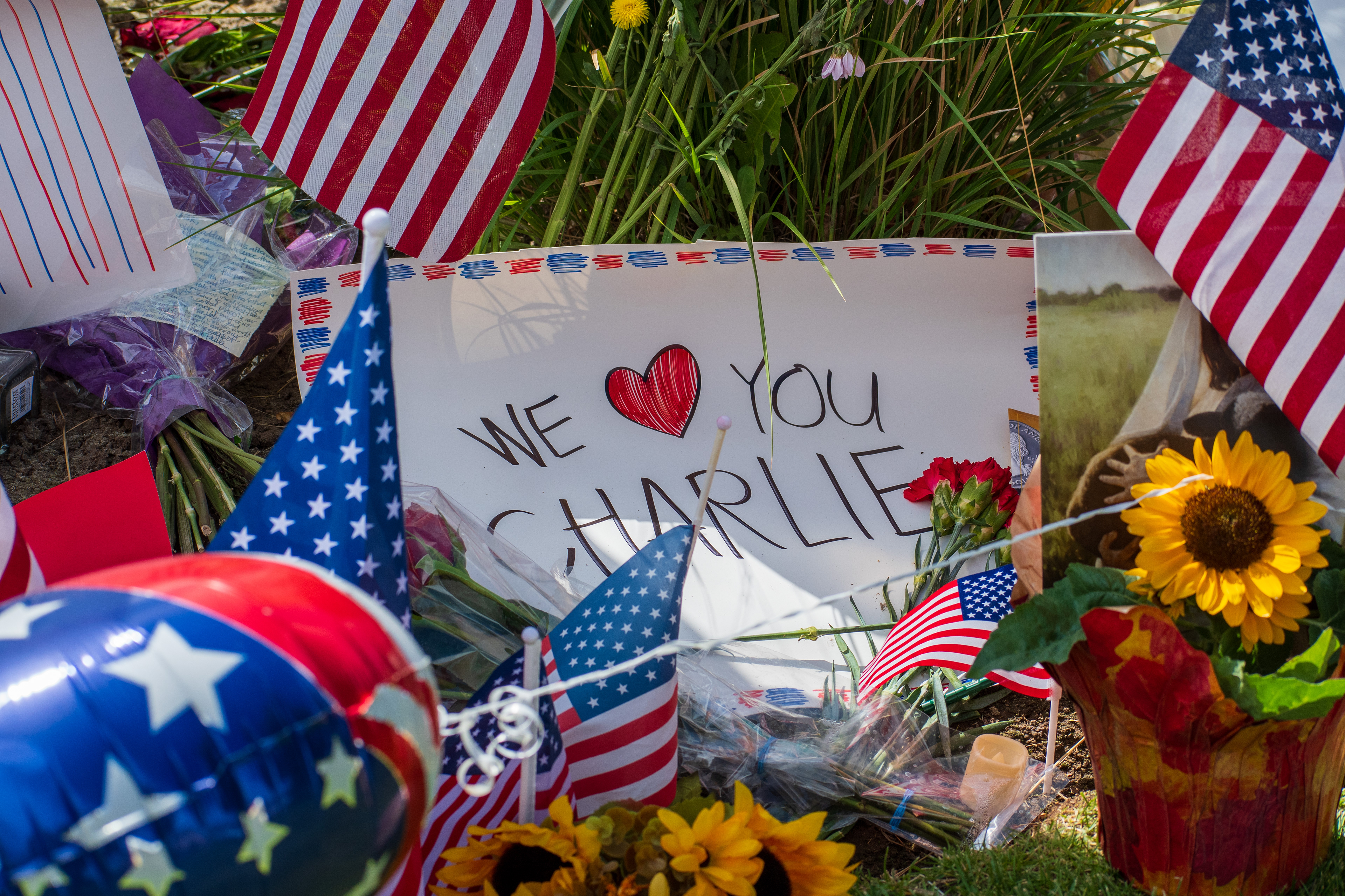OREM, UTAH – SEPTEMBER 12, 2025: A poster reading “WE ❤️ YOU CHARLIE” is displayed at a memorial site for Charlie Kirk outside Timpanogos Regional Hospital. Surrounded by American flags, red roses, a sunflower, and a star-spangled balloon, the tribute includes photographs and scenic imagery arranged on the grass. © Charles‑McClintock Wilson / ZUMA Press